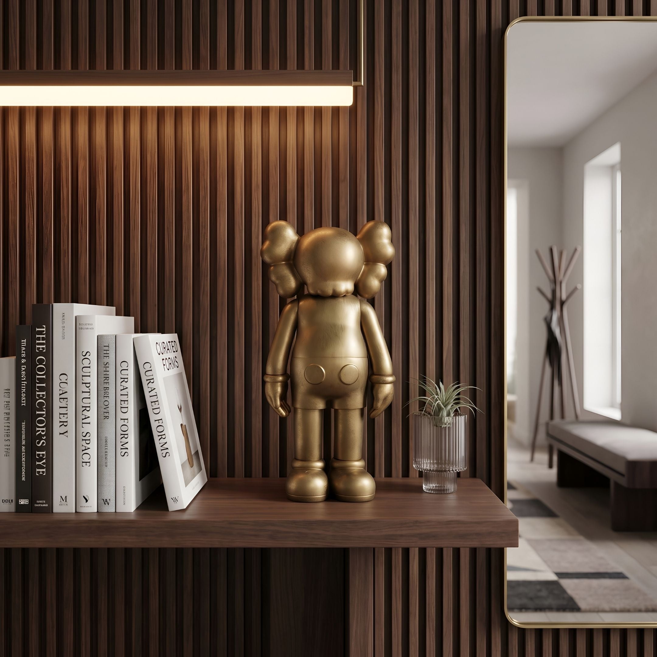 Antique Brushed Gold Iconify Standing Figure, 20cm, on a wood shelf beside books and a small potted plant near a wall mirror.