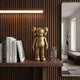 Antique Brushed Gold Iconify Standing Figure, 20cm, on a wood shelf beside books and a small potted plant near a wall mirror.