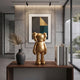 Champagne Satin Gold Iconify Standing Figure (20cm) on a wooden console table beside a dark vase and books, with abstract wall art behind it.
