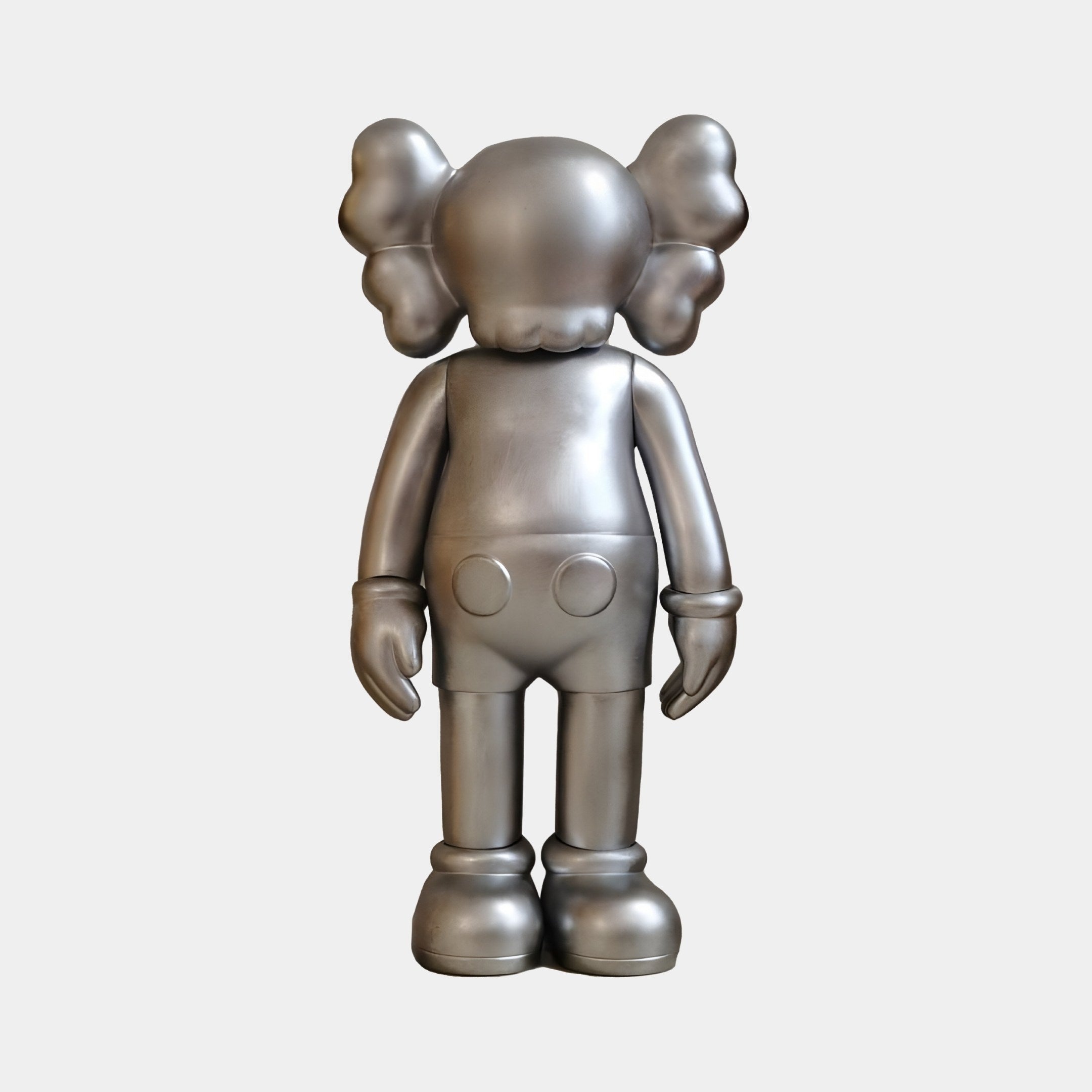 The Titanium Slate Iconify Standing Figure - 20cm by Giant Sculptures is a contemporary décor piece, featuring a cartoon character with rounded limbs, oversized shoes, and large ears resembling crossed bones, standing upright against a plain background.