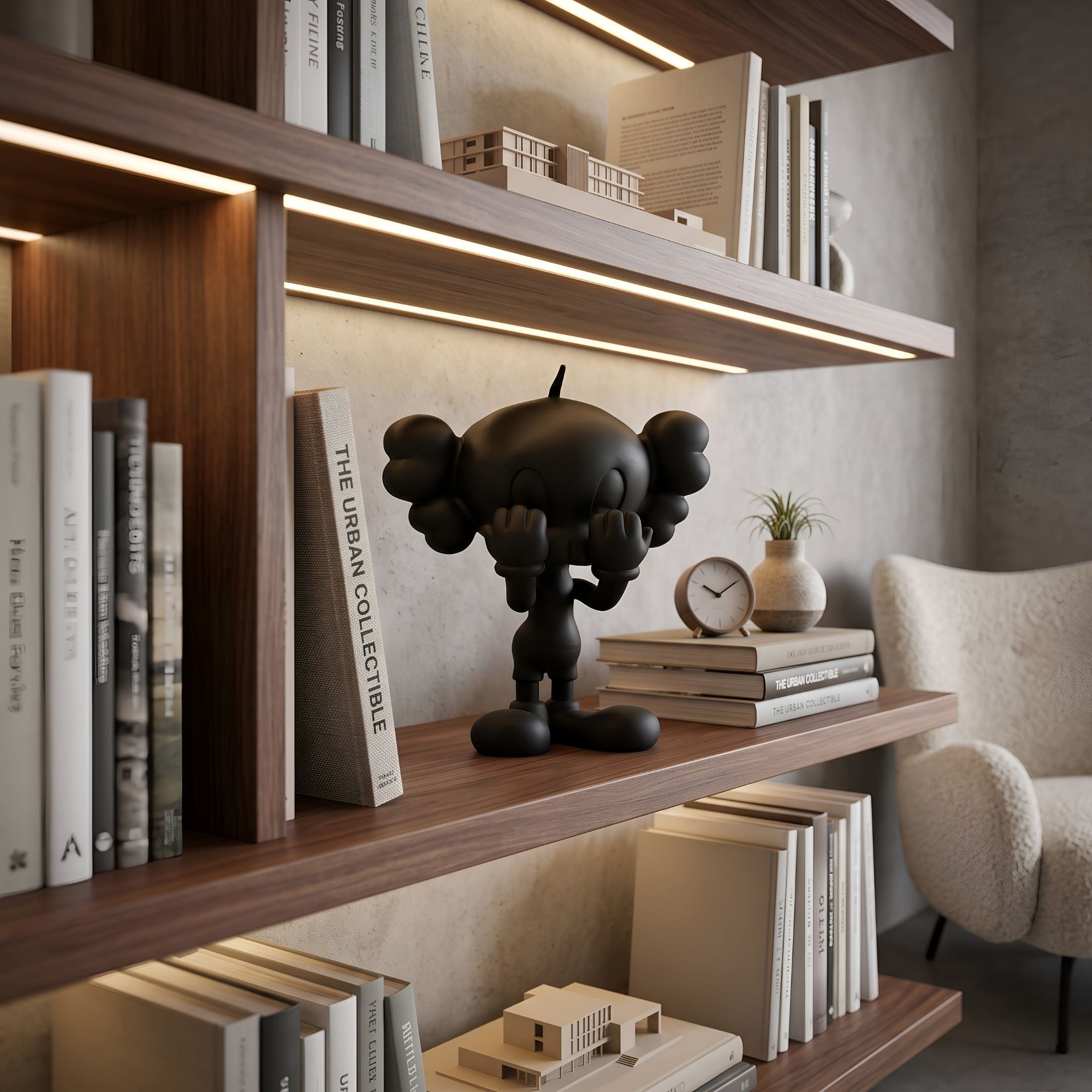 Black Iconify Tweeto Figure - 20cm by Giant Sculptures, hands covering its mouth, displayed on a wooden bookshelf beside books and a clock.