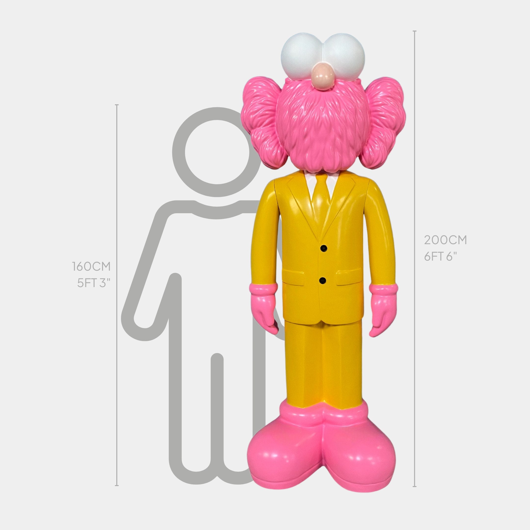 The Giant Sculptures Sunbeam Yellow Suit Iconify CEO Sculpture - 200cm features a bold resin design with a pink face, hands, feet, and white eyes, shown next to a gray outline of a person for scale.
