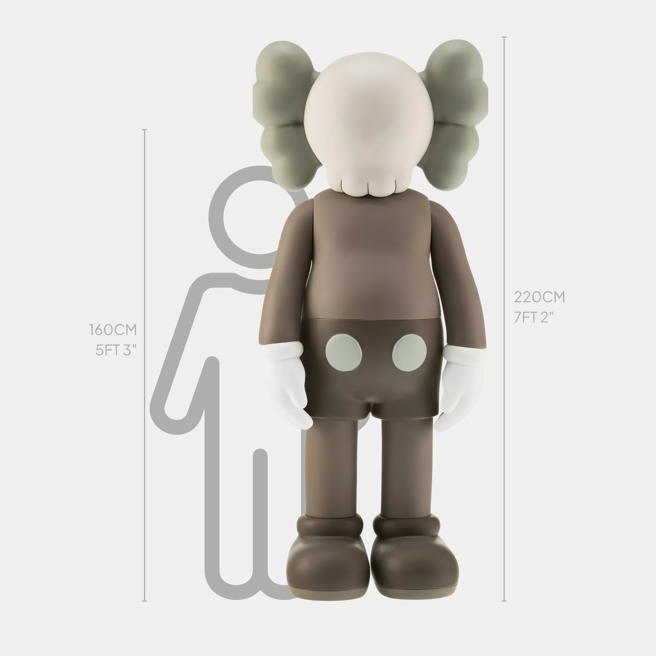 The Hazelnut Brown Iconify Standing Sculpture by Giant Sculptures is a 220 cm (7 ft 2 in) tall, grey cartoon figure with a round head, crossed eyes, gloves, and large shoes. It adds a quirky touch to interiors and stands beside a 160 cm (5 ft 3 in) human outline for size reference. Crafted from premium resin.