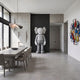 Soft Grey Iconify Standing Sculpture, 220cm, by Giant Sculptures, shown in a dining room against a dark accent wall near concrete panels and a long table.