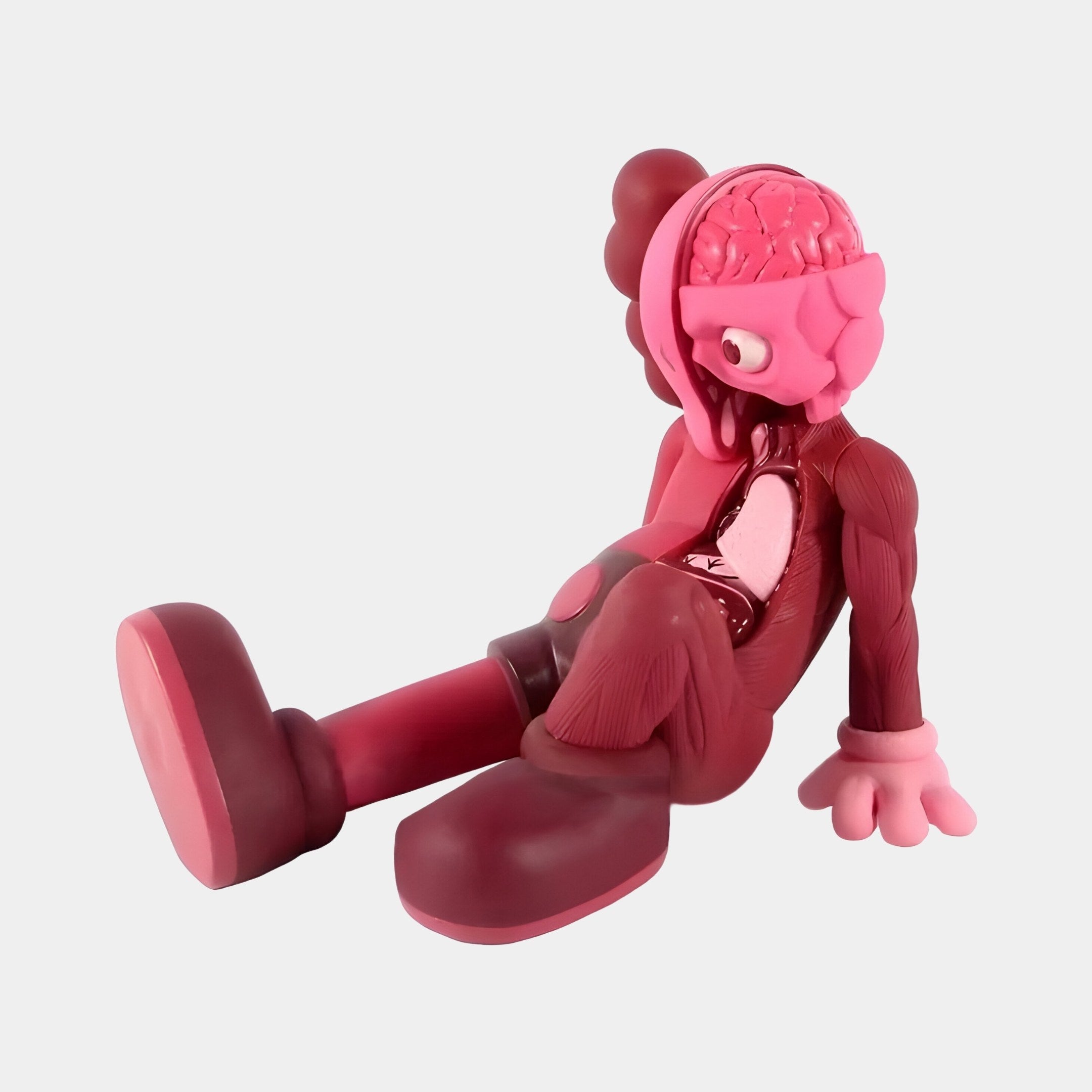 The Blush Ruby Iconify Anatomy Figure by Giant Sculptures is a 23cm resin collectible in pink and maroon. It elegantly sits with one hand on the ground, legs outstretched, revealing stylized internal organs. Its rounded features make it an eye-catching modern décor piece against a plain backdrop.