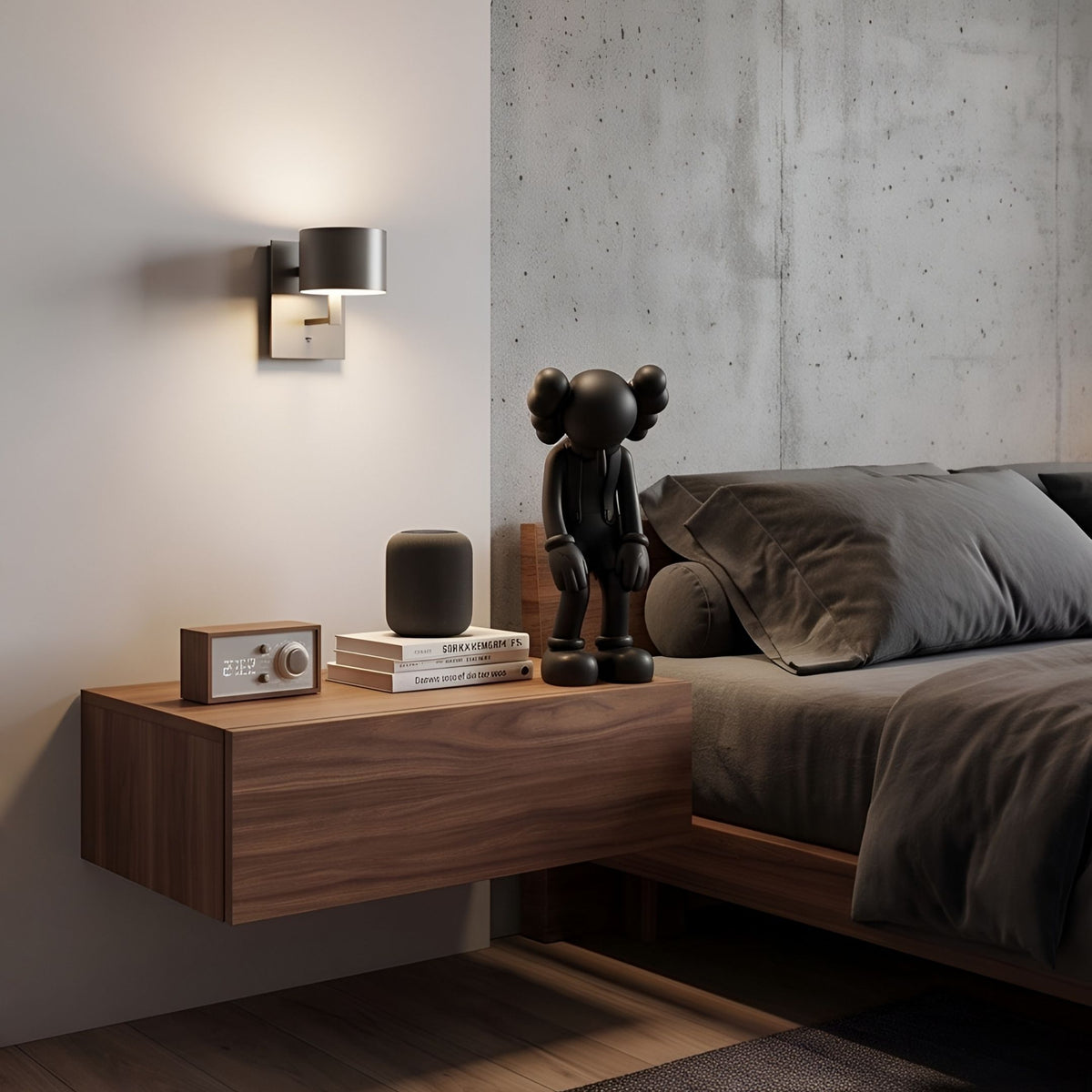 Midnight Black Iconify Burden Figure - 28cm on a floating walnut nightstand in a bedroom, standing with bowed head beside books and a speaker.