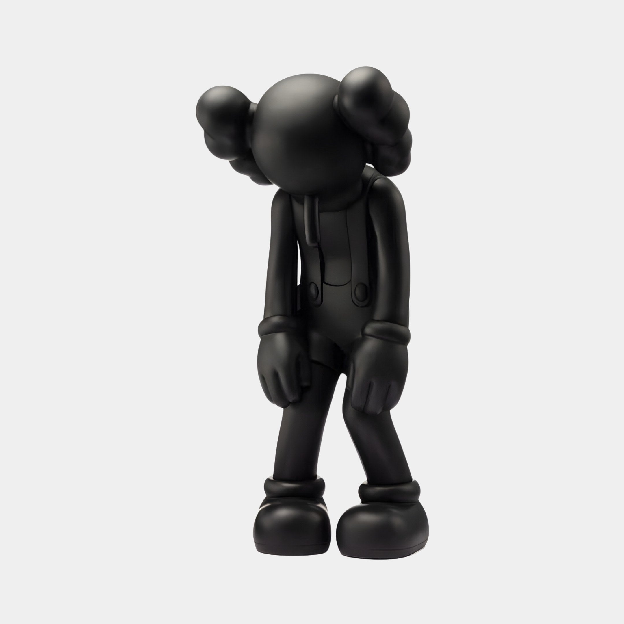 The 28cm Midnight Black Iconify Burden Figure by Giant Sculptures features a matte finish, bowed head, and arms hanging down. It has a featureless round face and cartoonish gloved hands, with cloud-like protrusions enhancing its contemporary pop-art aesthetic suggestive of dejection.