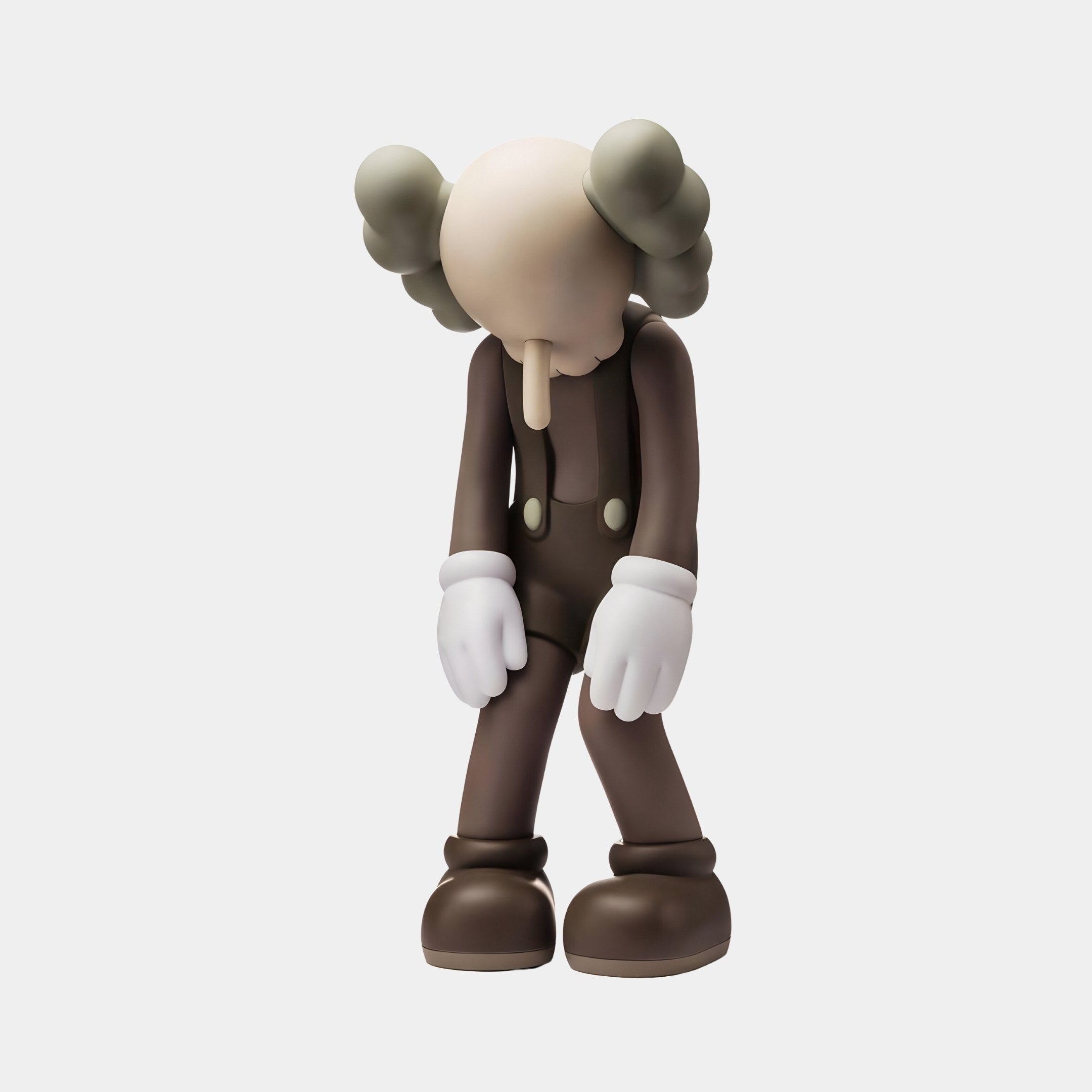 The Hazelnut Brown Iconify Burden Figure by Giant Sculptures, standing 28cm tall, leans forward with bone-shaped ears, a long nose, gloved hands and a featureless face. Made from high-quality resin, its dark outfit with buttons and thick shoes contrasts against a plain white background.