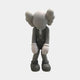 The 28cm Soft Grey Iconify Burden Figure by Giant Sculptures features large ears, a trunk-like nose, and gloved hands, hunched in a thoughtful pose. Dressed in overalls and large shoes, this character captures the essence of contemporary sculpture against a simple backdrop.