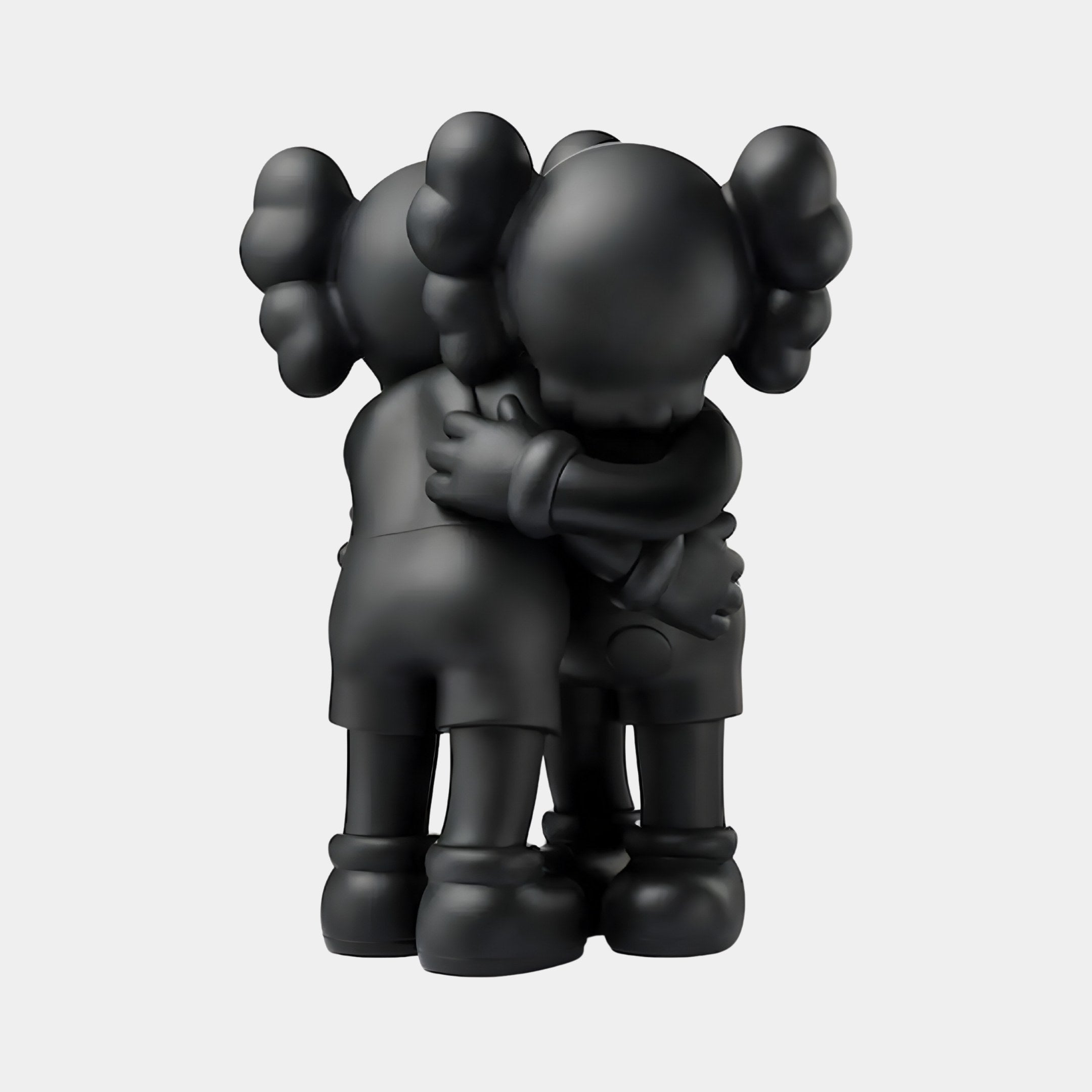 The Giant Sculptures Obsidian Black Iconify Embrace Figures, 28cm tall, feature sleek resin crafting with round heads, cross-shaped eyes, and large rounded hair spikes. Dressed in shorts and shoes, the minimalist design beautifully captures a comforting human embrace.