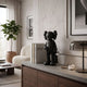 Midnight Black Iconify Black Furry Toy Figure, 28cm matte black designer figure with X-shaped eyes, displayed on a sideboard beside books in a living room.