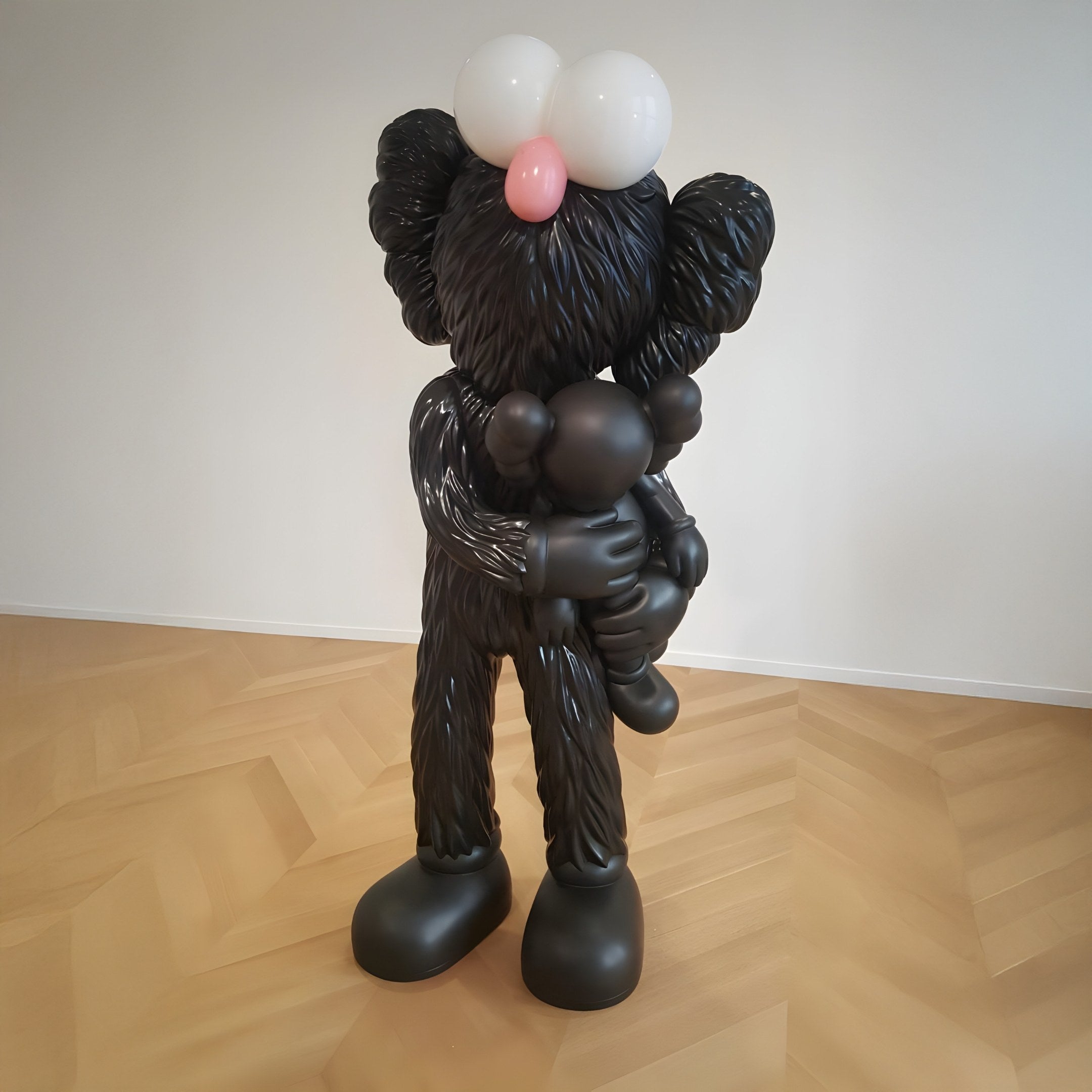 The Giant Sculptures Iconify Loving Furry Figure is a large, obsidian black sculpture with oversized eyes and a pink nose on a light wooden floor. It embraces a smaller figure in a playful, cartoonish style, showcasing pop-art flair. Length: 28cm.