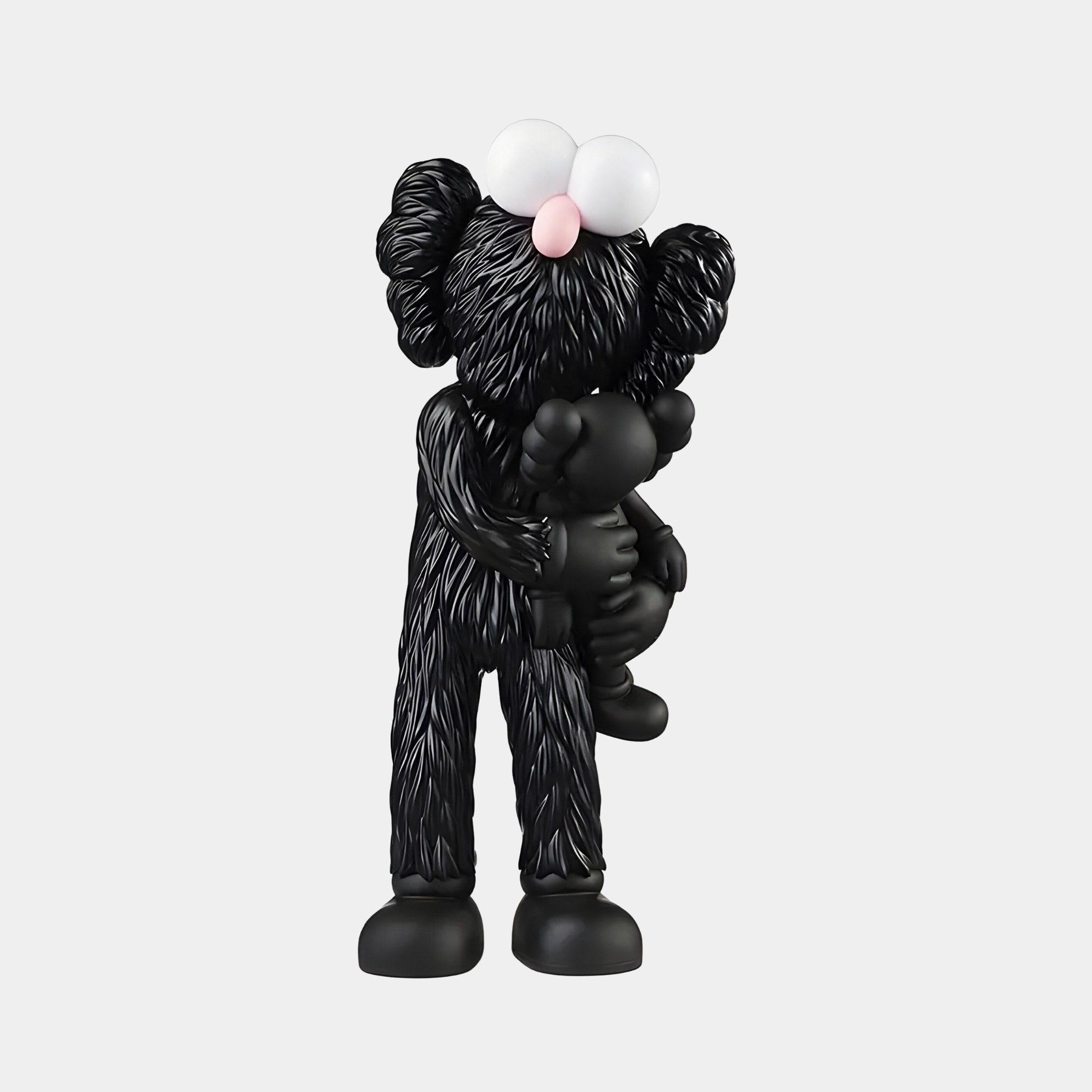 The Giant Sculptures Obsidian Black Iconify Loving Furry Figure - 28cm is a pop-art statue of a black, cartoon-like character with large eyes and ears, cradling a smaller figure. Its pronounced textures are striking against the plain white background.