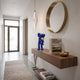 Deep Blue Iconify Loving Furry Figure, 28cm, on a floating walnut console in a hallway with a round brass mirror and pendant light.