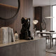 Midnight Black Iconify Melancholy Sitting Figure, 28cm, seated on a sideboard with books and decor in a dining room with wood-paneled walls.