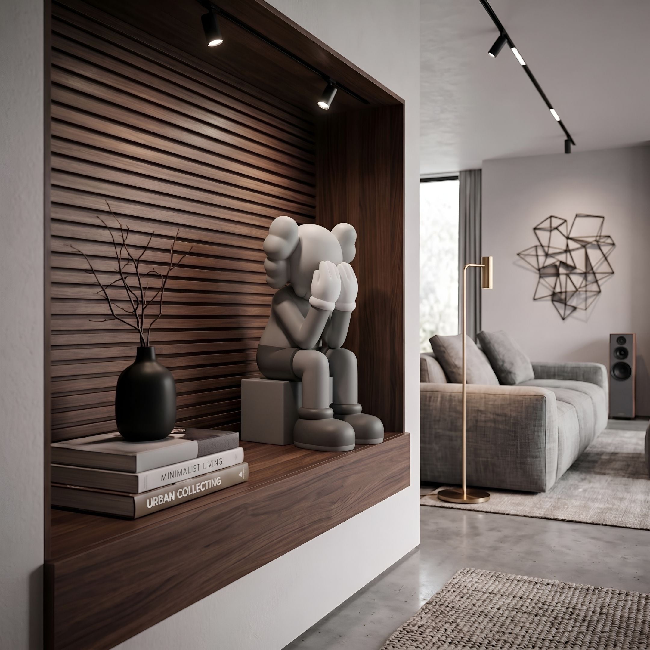 Slate Grey Iconify Melancholy Sitting Figure (28cm) on a wood shelf, seated on a block plinth with head in white-gloved hands, near books and a black vase in a living room.