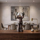 Hazelnut Brown Iconify Silent Cry Figure, 28cm, hands covering face, displayed on a wooden sideboard in a dining room with abstract wall art.