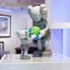 The Soft Grey Iconify Atlas Figure by Giant Sculptures, standing at 30cm, features a larger figure holding a globe and a smaller one reaching for it. Set on a white surface with a blurred background, its ideal for modern interiors.