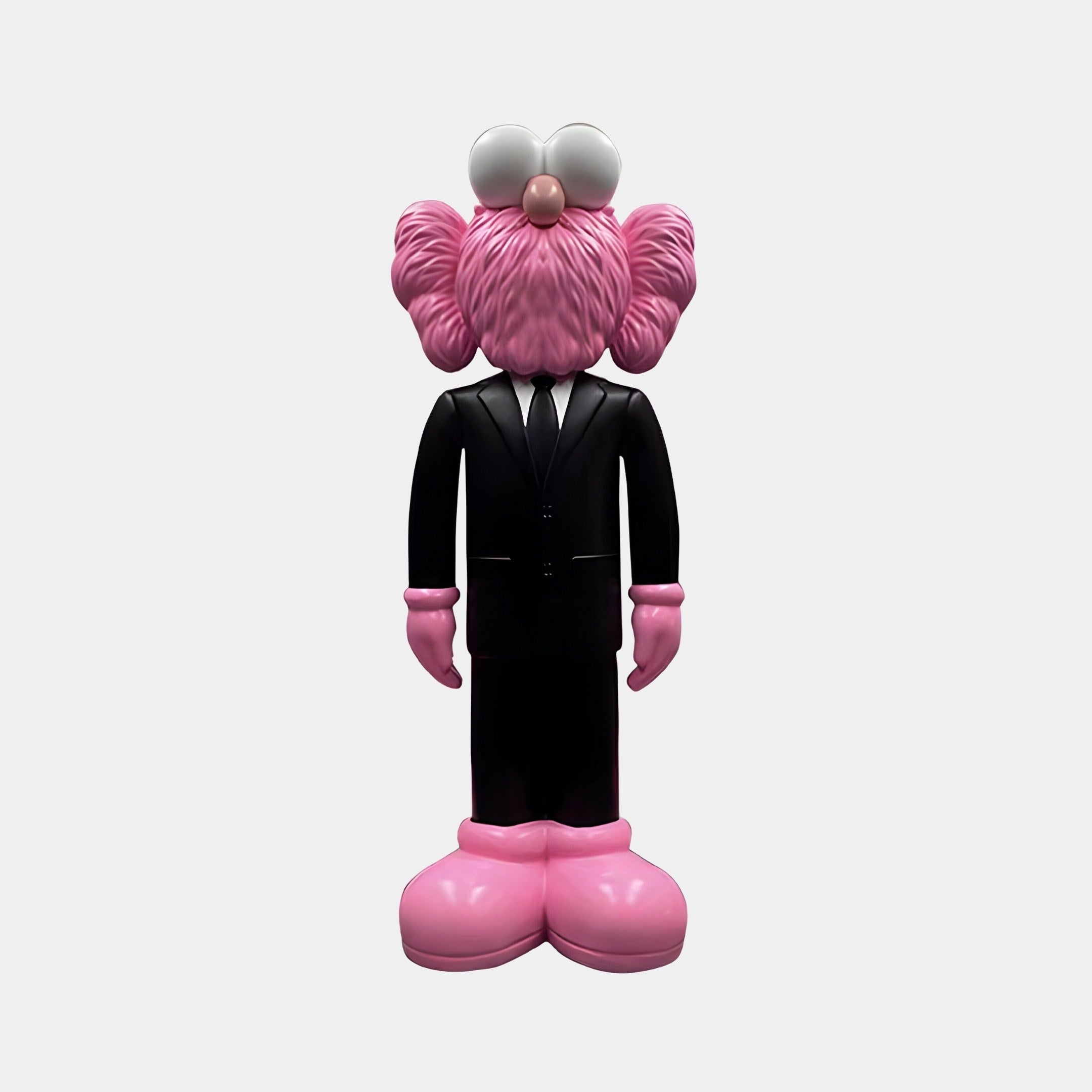 The Midnight Black Iconify CEO Figure by Giant Sculptures features a pink, fuzzy character in a black suit and tie. It has large white eyes on its head and oversized pink shoes, all set against a plain white background to enhance its bold contrast.