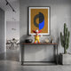 Golden Maize Yellow Iconify Chuckle Figure, 30cm, on a console table in a grey entryway beneath abstract wall art, near a cactus and clock.