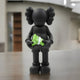 The 30cm Midnight Black Iconify Dollars Figure by Giant Sculptures captures financial ambition with exaggerated features holding green bills, set against a sleek indoor surface that enhances its depth amid a blurred neutral-toned background and wooden structure.