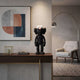 Obsidian Black Iconify Furry Figure, 30cm, on a console table with abstract wall art, lamp, and armchair in a modern living room setting.