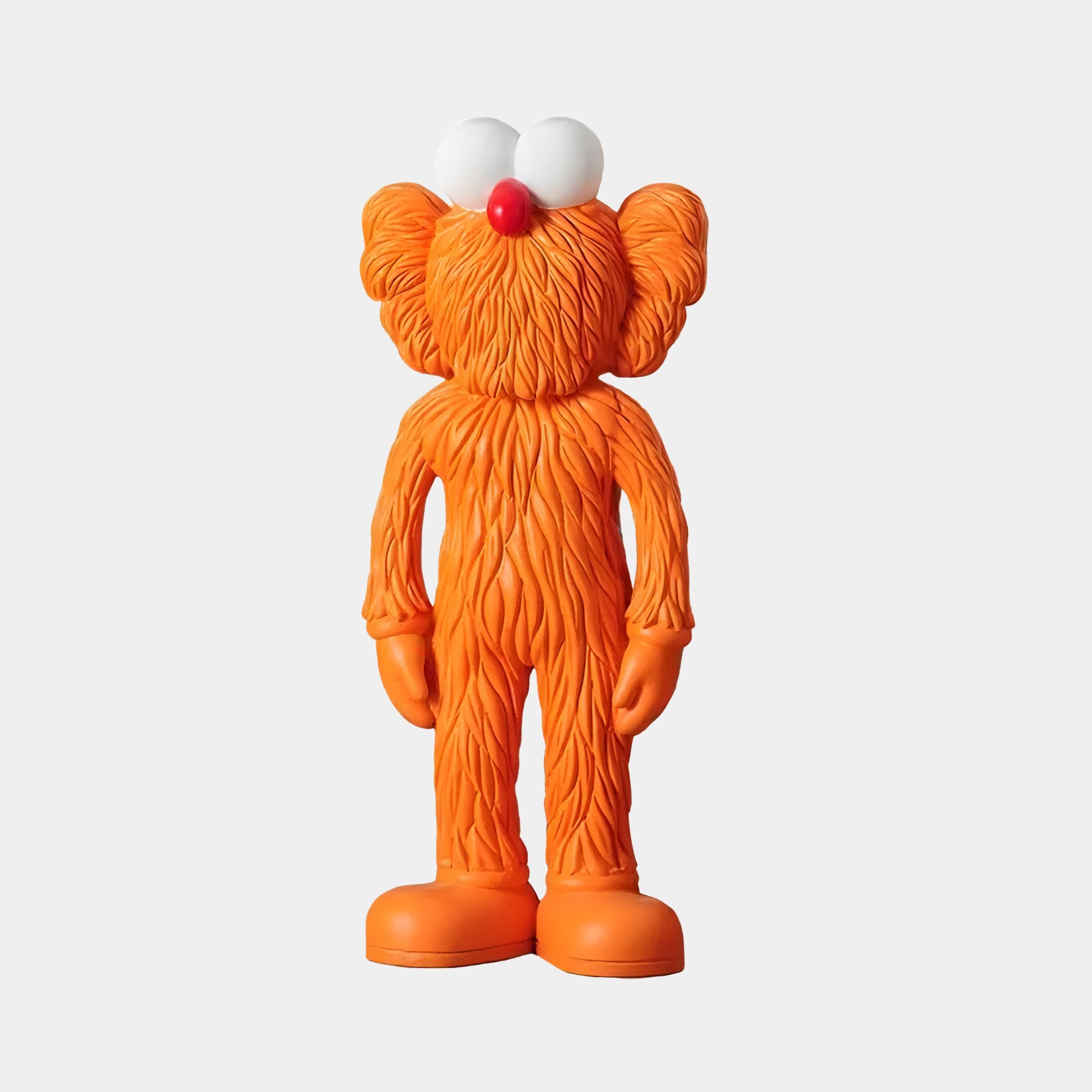 The Giant Sculptures Flame Orange Iconify Furry Figure - 30cm stands upright with an orange, fuzzy body, large white eyes, a red nose, oversized feet, and elongated arms with mitten-like hands against a plain white background.