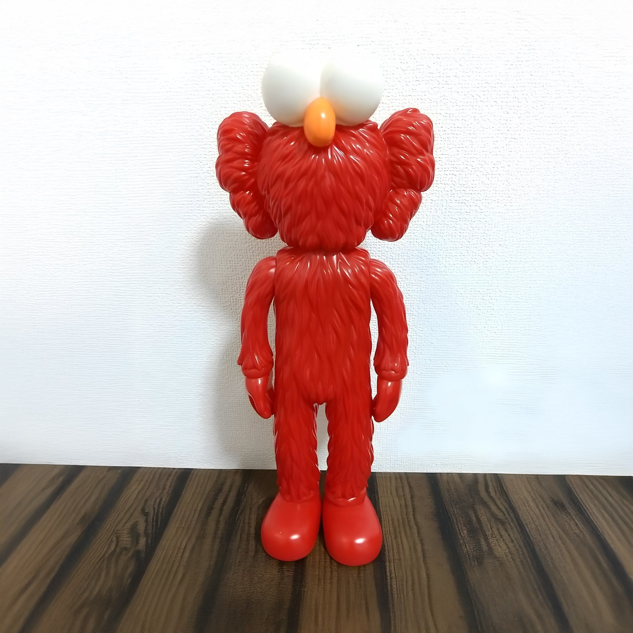 The Fiery Red Iconify Furry Figure by Giant Sculptures showcases a fuzzy toy with large white eyes, an orange nose, and exaggerated hands. Standing upright on wood against a plain white background, this 30cm collectible is a contemporary pop art must-have.