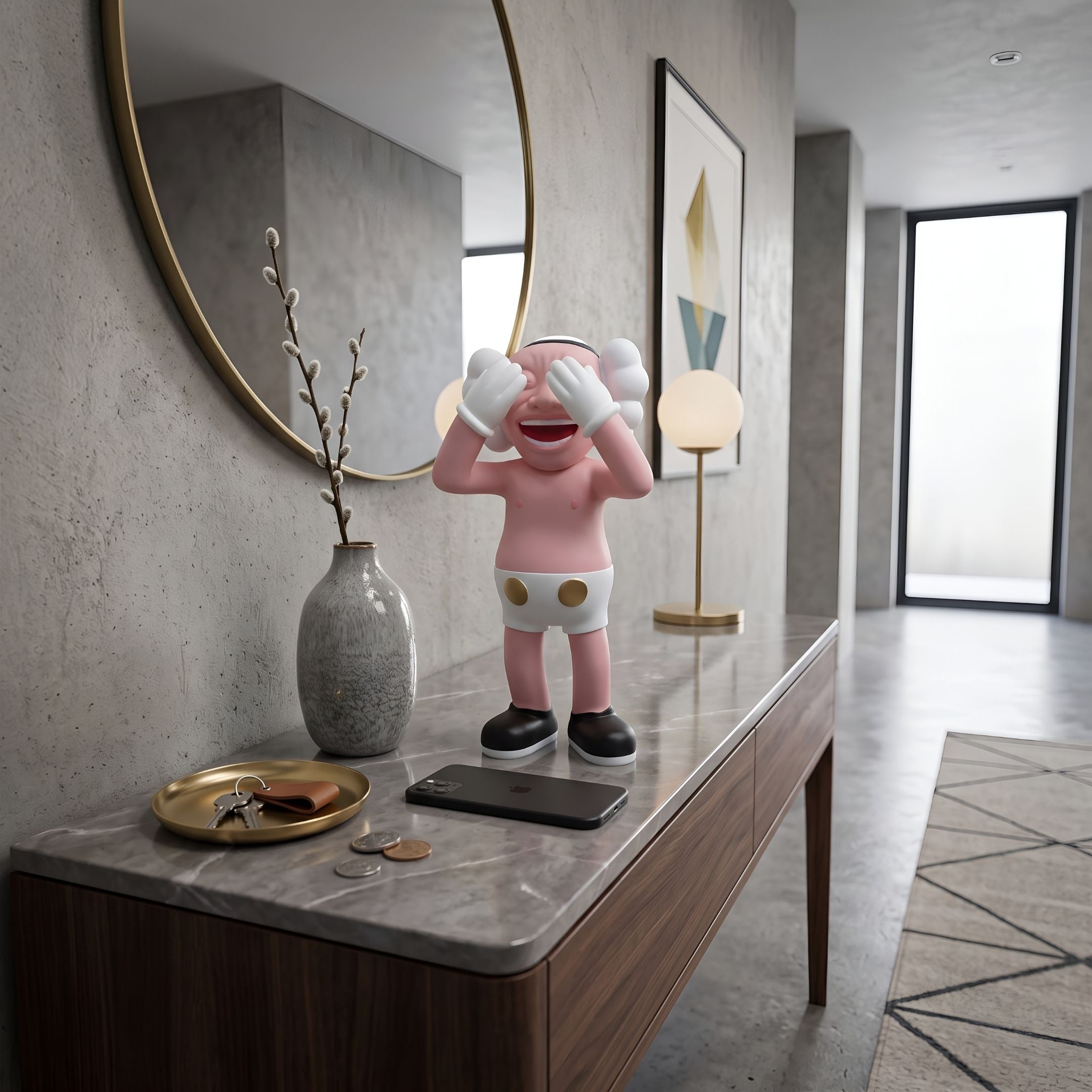 Petal Pink Iconify Jolly Figure, 30cm, covering eyes and laughing on a marble entryway console beside a round mirror and ceramic vase.