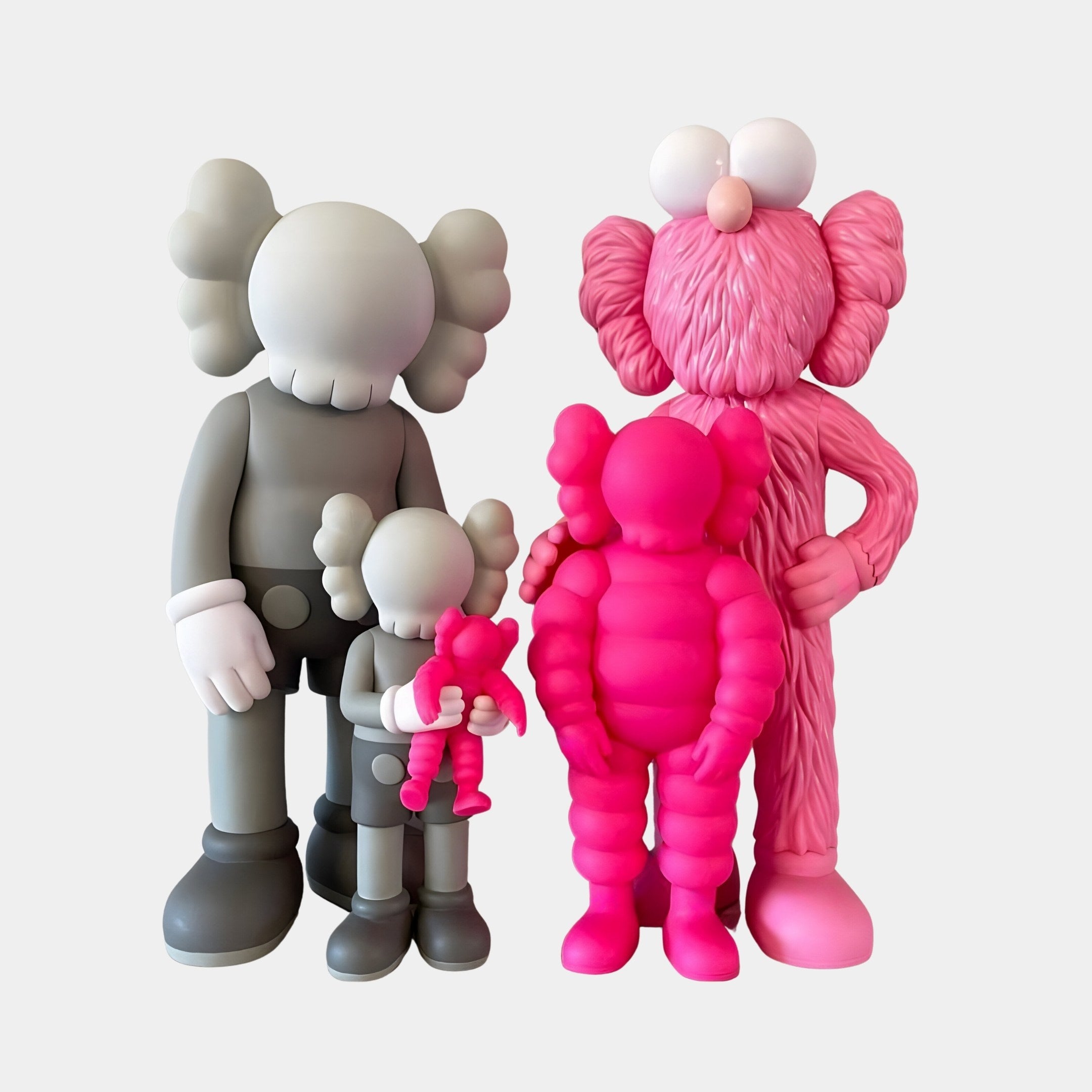 The Iconify III All-Together Figure by Giant Sculptures features four vivid cartoon-like figures with large heads and X eyes. The gray pair, a large and smaller figure holding a tiny pink one, contrasts the pink duo. These resin sculptures bring charm to any modern interior.