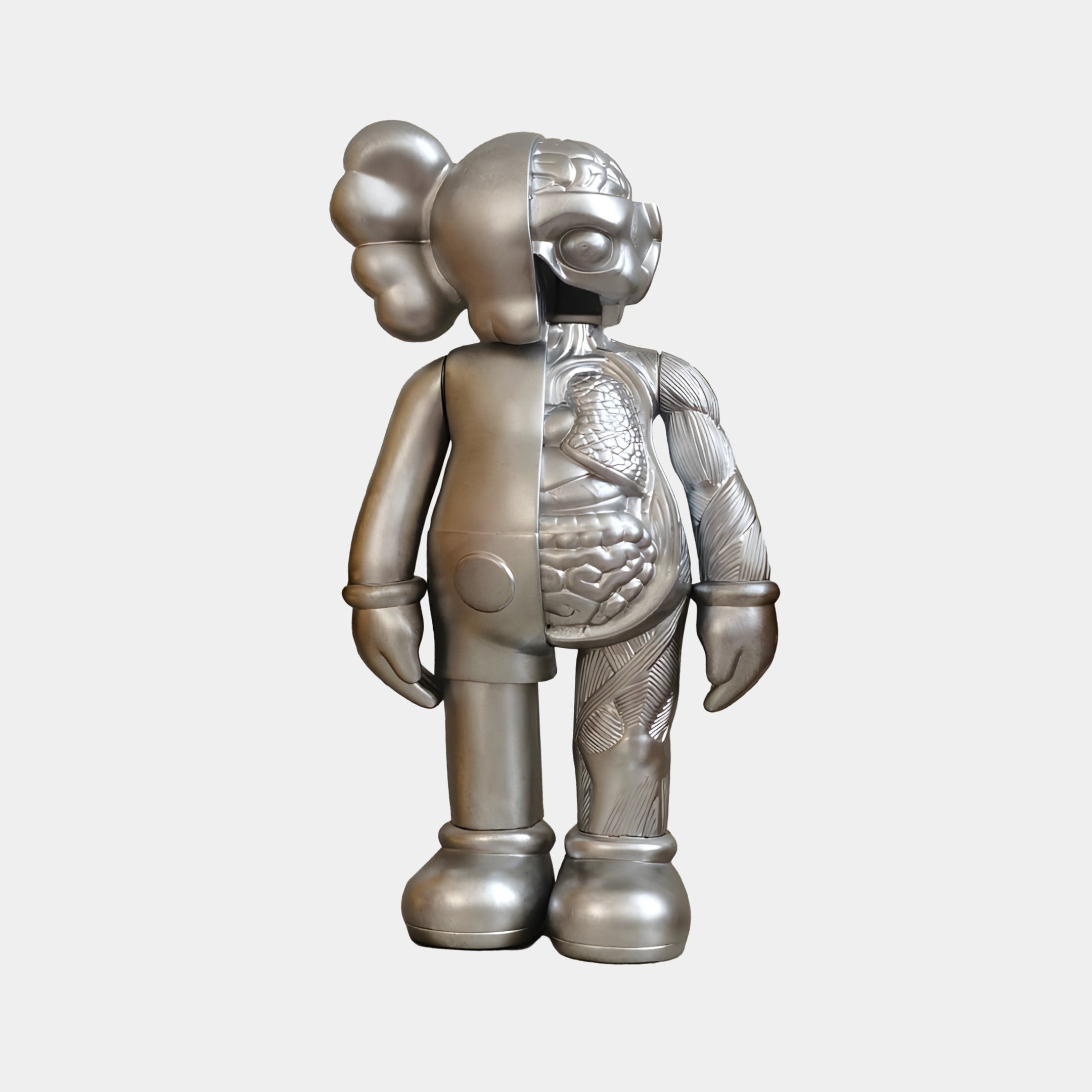 The Titanium Slate Iconify Anatomy Figure by Giant Sculptures is a striking 37cm contemporary art piece. With its cartoon-like figure featuring rounded ears, it contrasts surface details on one side with intricate anatomical structures on the other, epitomizing an anatomical art sculpture.