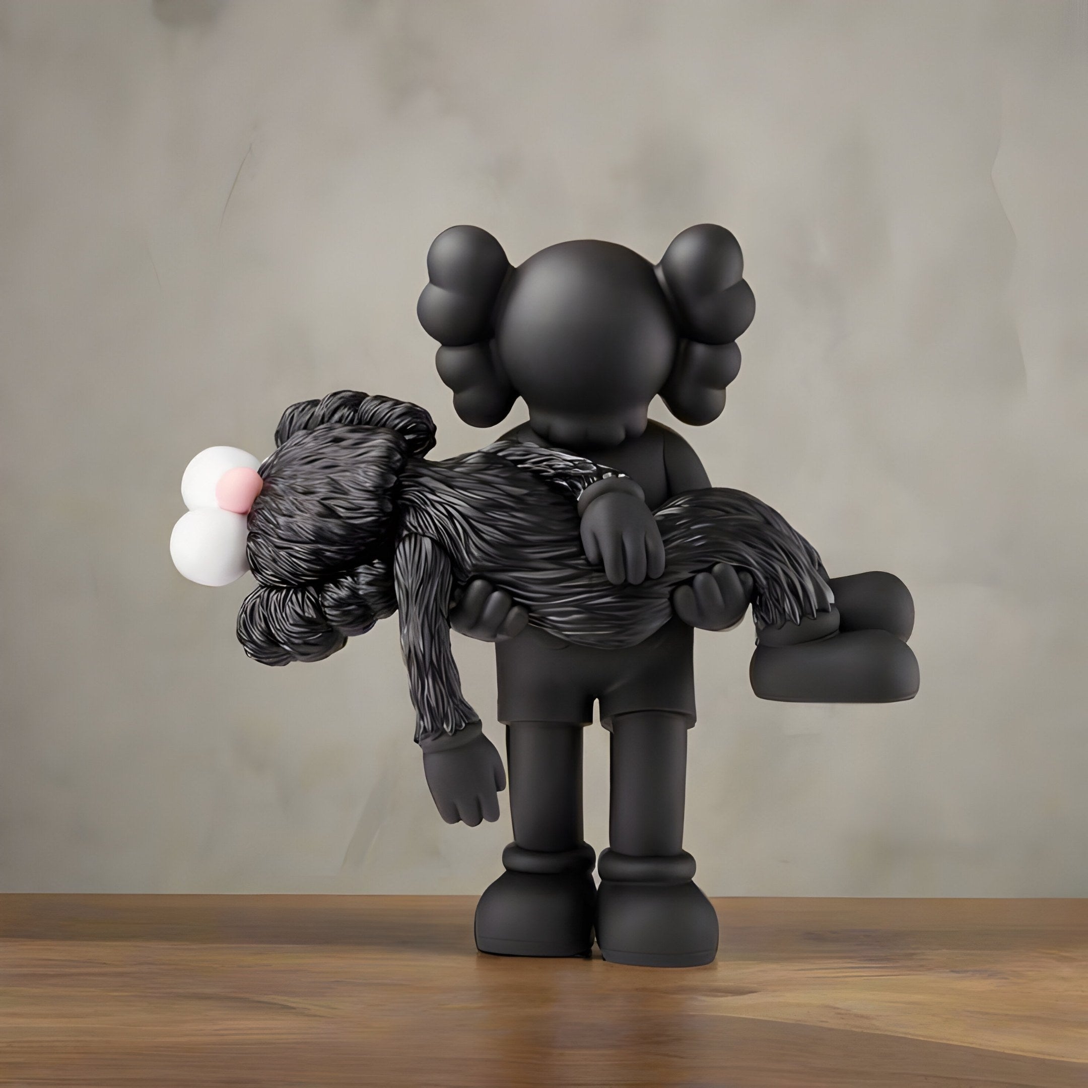 The Obsidian Black Iconify Rescuing Figure by Giant Sculptures is a 38cm black figurine with unique ear shapes holding a furry character with pink and white eyes, set against a muted gray background on wood, ideal for modern interiors.