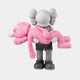 The Petal Pink Iconify Rescuing Figure by Giant Sculptures features a grey stylized figure with crossed-out eyes holding a limp, petal pink companion. Both have round shapes and textured hair, set against a white background to create a striking decorative piece.