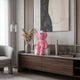 Petal Pink Iconify Furry Sitting Figure, 40cm, seated on a white block atop a media console in a living room with wood cabinetry and abstract wall art.