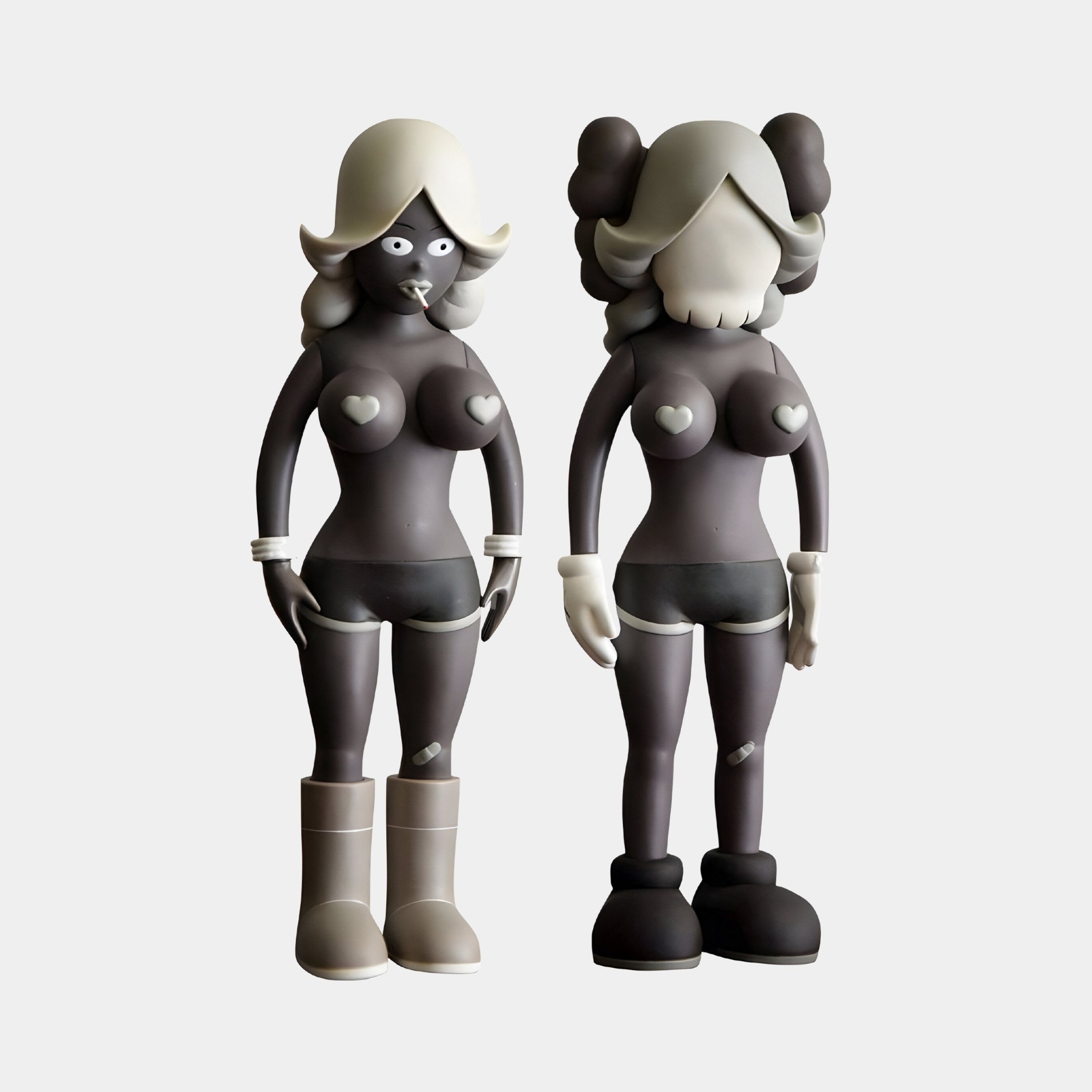 The Smoky Umber Gray Iconify Vera Dolls Figures by Giant Sculptures captivate with their smoky umber gray, bubble-shaped heads, heart chest details, distinct hair and footwear styles. At 40cm tall, they stand side by side against a plain backdrop, sparking artistic intrigue.