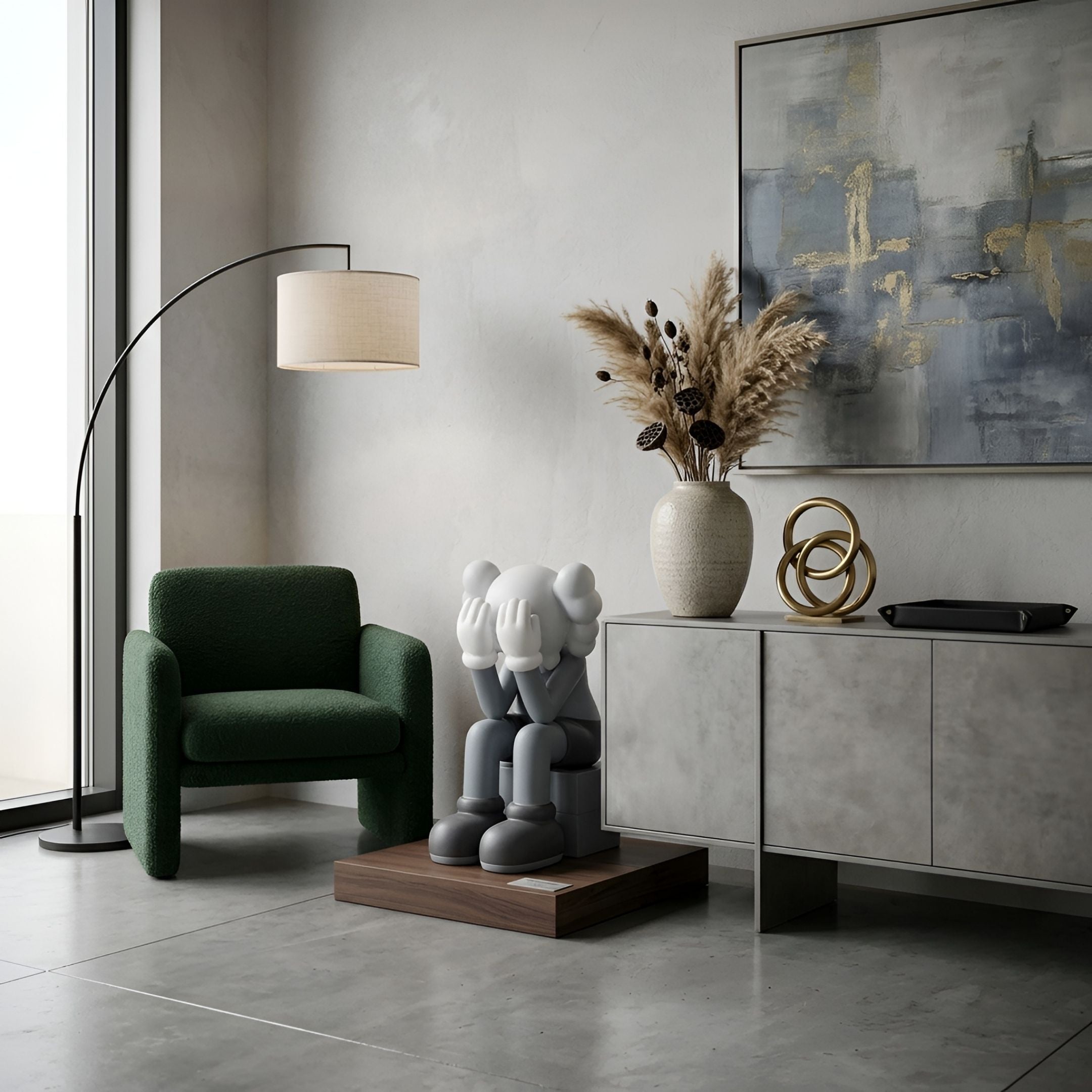 Slate Grey Iconify Melancholy Sitting Sculpture, 70cm, on a wooden plinth beside a green armchair and grey sideboard in a living room setting.