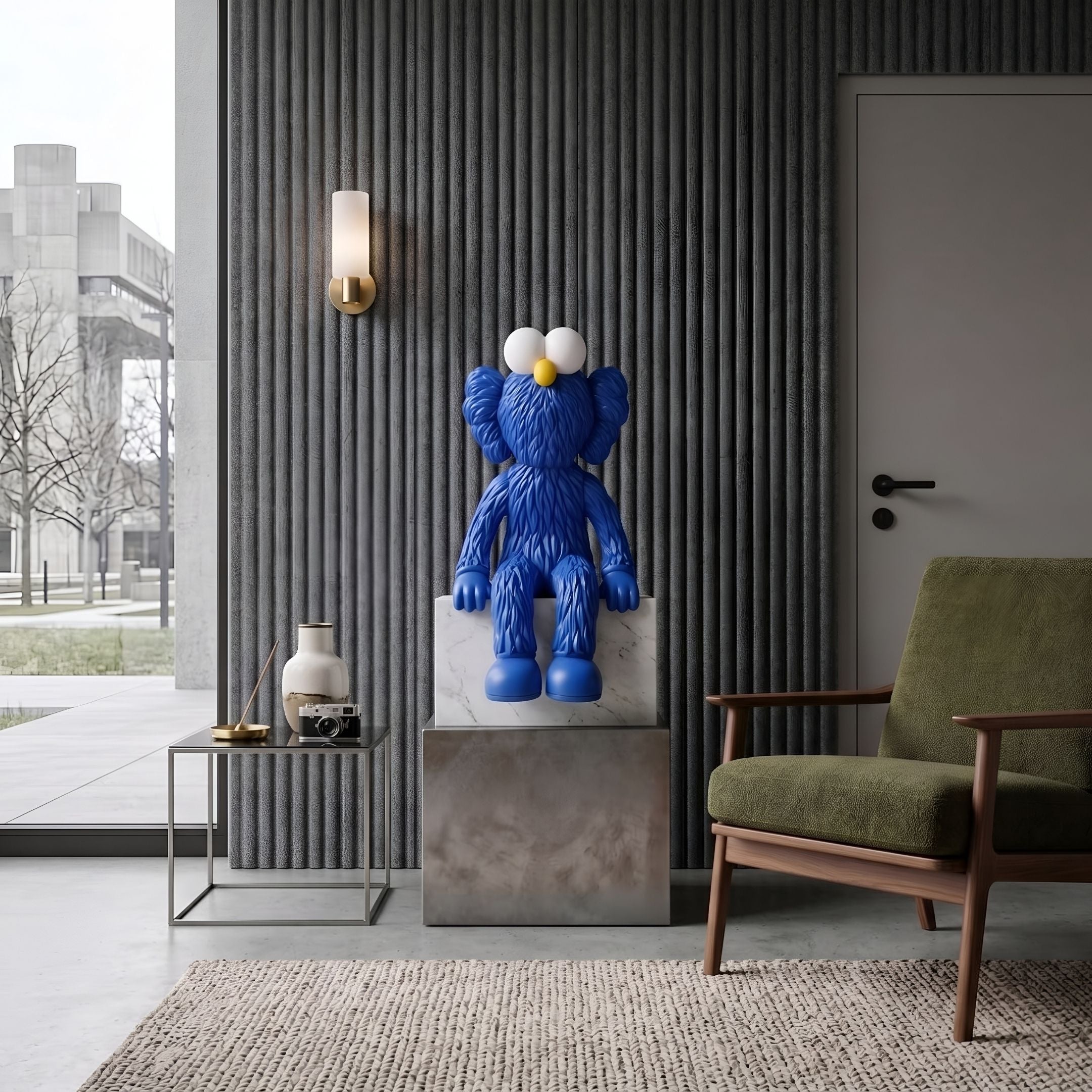Deep Blue Iconify Furry Sitting Sculpture, 70cm, on a stone pedestal beside a green armchair in a living room with ribbed grey wall paneling.