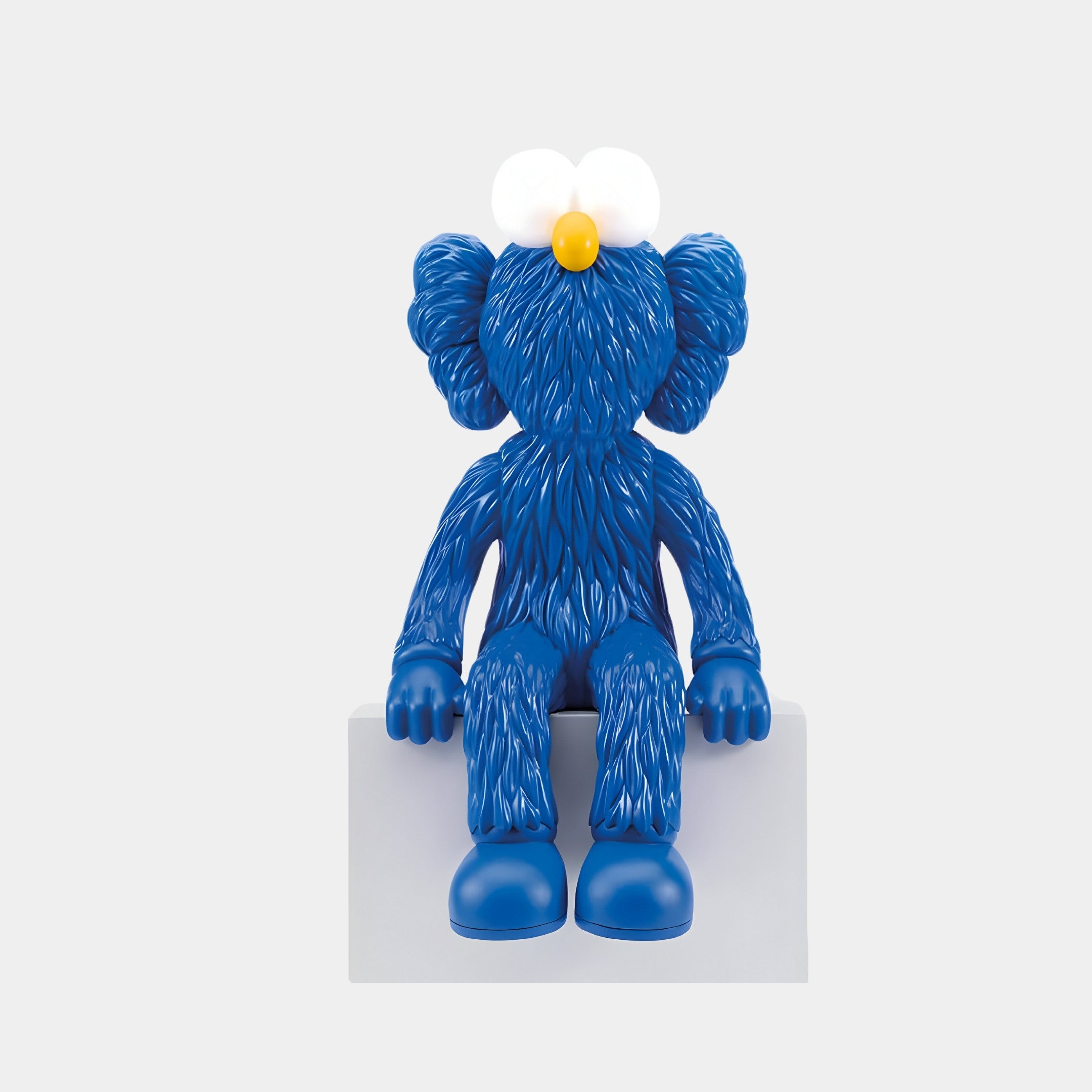 The Giant Sculptures Deep Blue Iconify Furry Sitting Sculpture is a 70cm figure with exaggerated features and artistic flair. It boasts large white eyes, a yellow nose, oversized ears, and a fur-like texture while sitting on a gray block to enhance contemporary interiors.