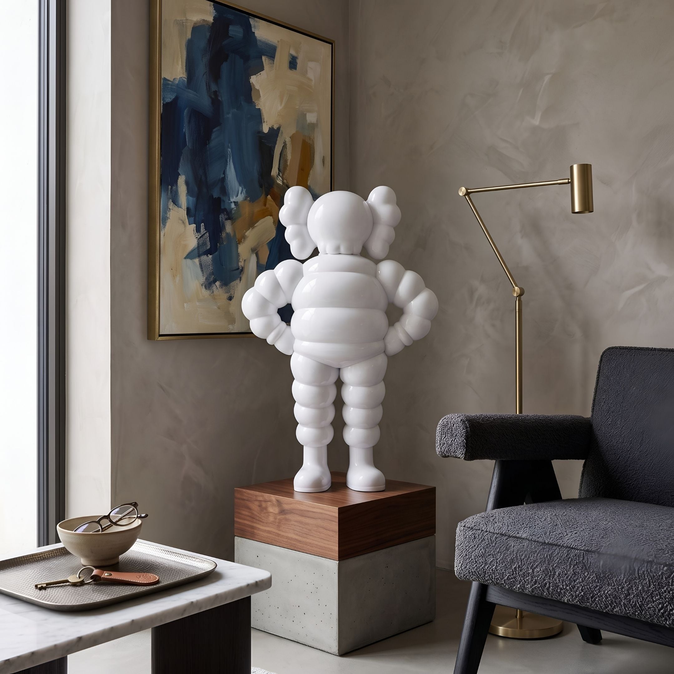 Cloud White Iconify Rollo Warrior Sculpture, 80cm, resin figure with hands on hips on a wood and concrete plinth in a living room beside a dark armchair and abstract wall art.