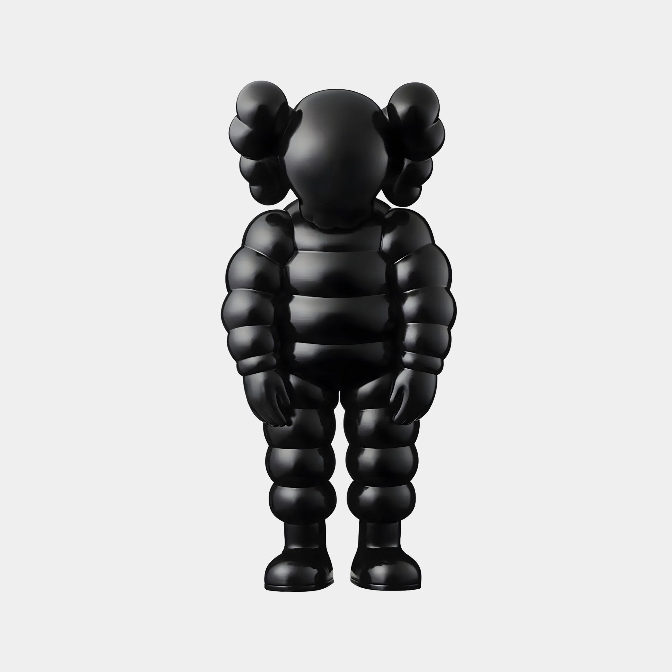 The Midnight Black Iconify Rollo Sculpture - 80cm by Giant Sculptures stands against a white background, its glossy finish highlighting round, bulbous features. With stylized limbs and cartoonish crossed-out eyes, it complements luxury interiors while embodying modern minimalist design.