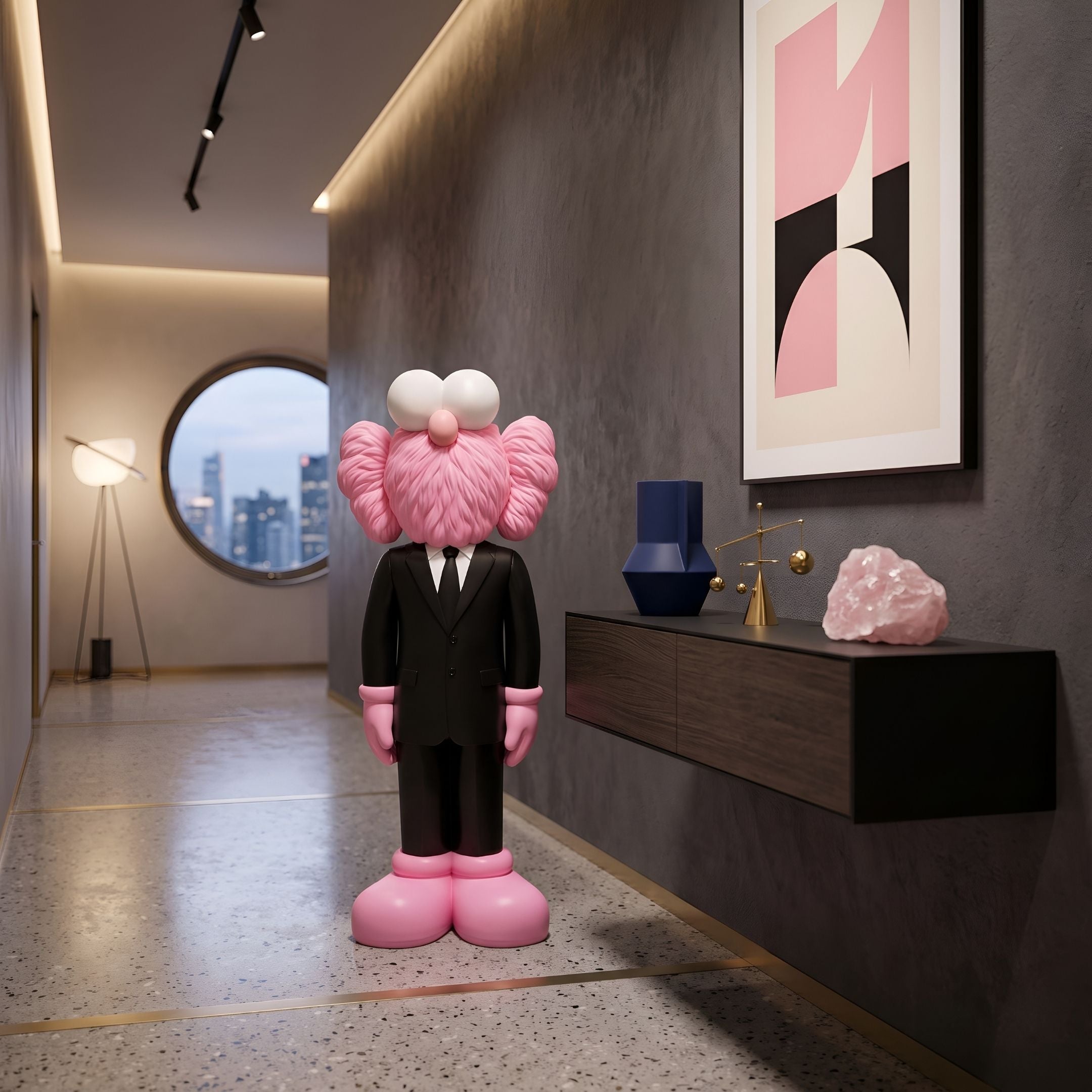 Black Suit Iconify CEO Sculpture, 90cm, pink cartoon figure in tailored black suit, standing in a hallway beside a wall-mounted console and framed abstract art.