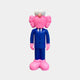 A pink creature with fuzzy hair and big white eyes stands upright, adorned in a Cobalt Blue Suit from the Iconify CEO Sculpture collection by Giant Sculptures, complete with pink gloves and oversized shoes, embodying contemporary artistry against a light gray background.