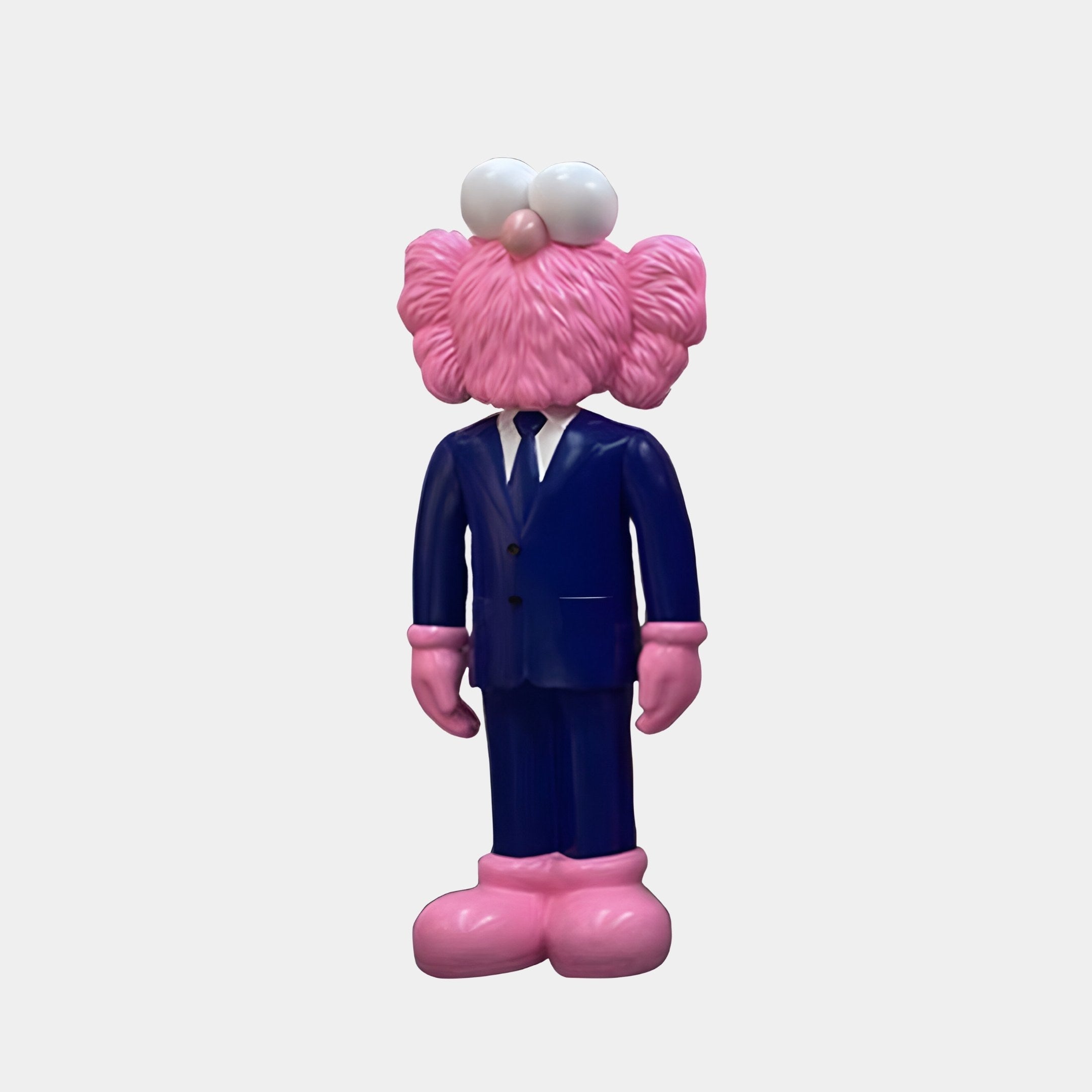 A pink, cartoonish figure with oversized eyes and large fluffy ears stands in a blue suit and pink shoes against a plain background. This textured, bearded sculpture from Giant Sculptures measures 90 cm tall.