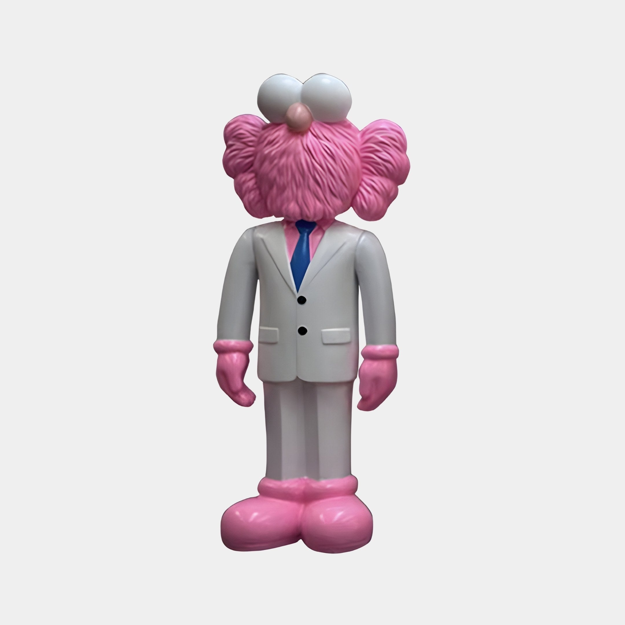 The White Suit Iconify CEO Sculpture by Giant Sculptures is a modern, sophisticated 90cm pink, furry character with a large head. It wears a white suit with a blue tie and pink gloves and shoes, standing upright on a plain background, radiating executive presence.