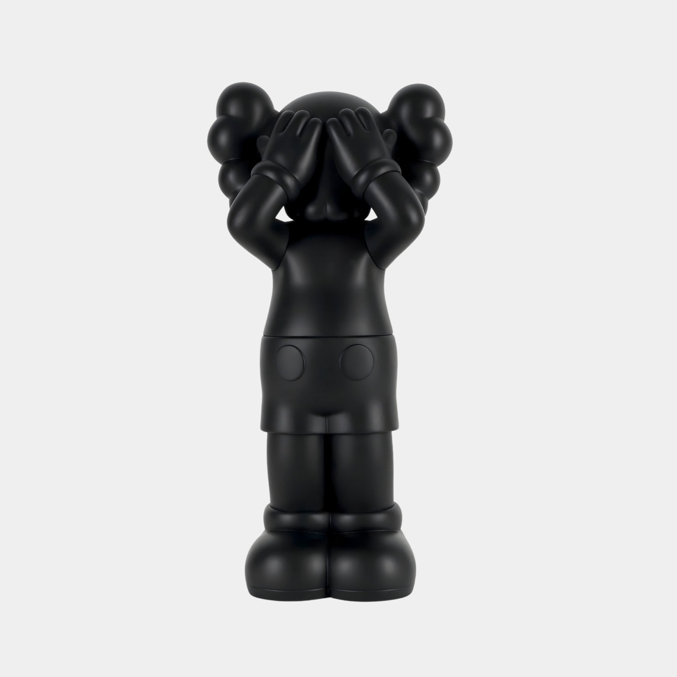 The Obsidian Black Iconify Silent Cry Sculpture by Giant Sculptures, standing 91cm tall, showcases a smooth, cartoonish design with rounded features and large shoes against a plain background. It stands upright covering its eyes, making it perfect for expressive interiors.