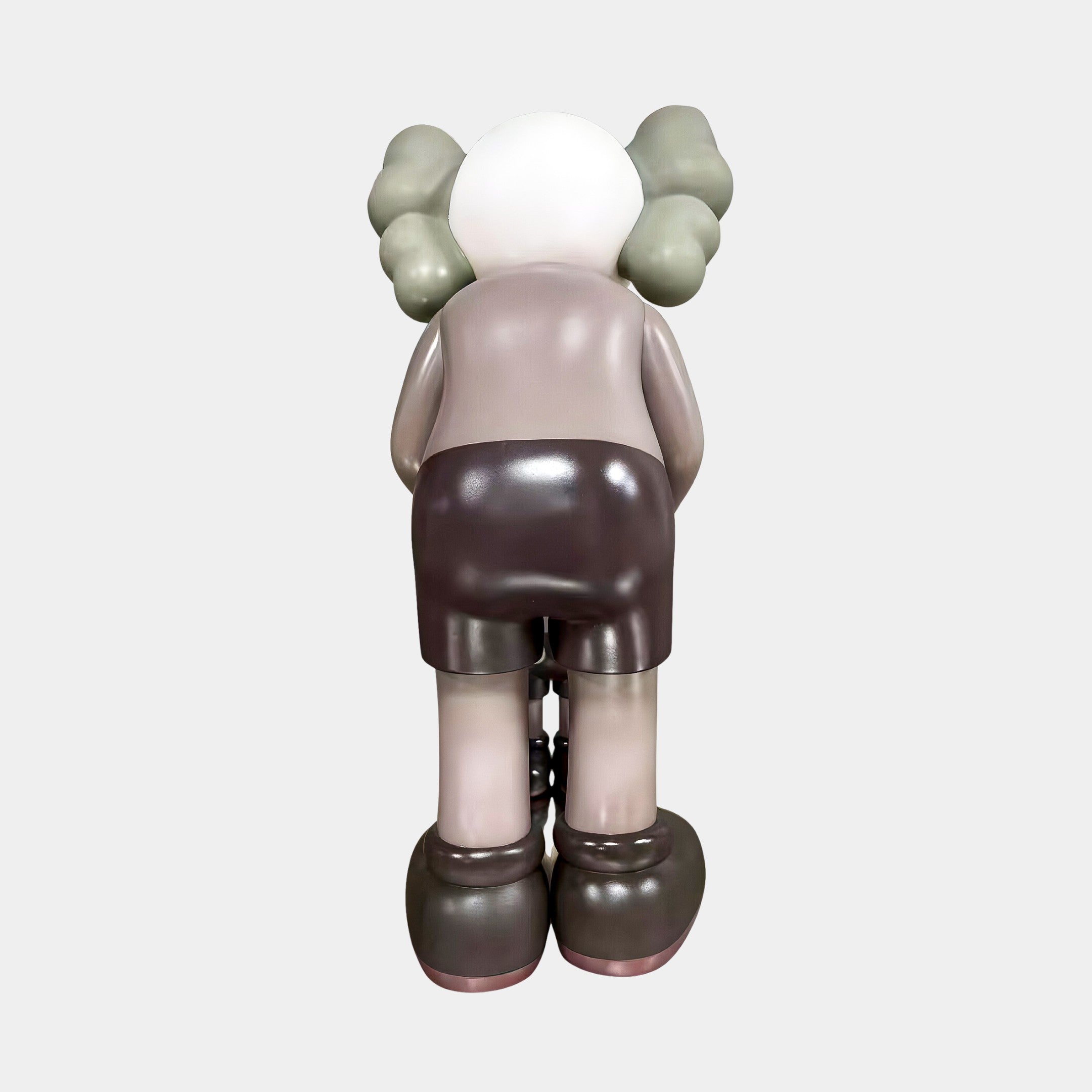 The Hazelnut Brown Iconify Atlas Figure by Giant Sculptures stands 30cm tall, bent forward with gray-green gloves and shoes, a white head, and grayish shorts—perfect for unique home office decor.