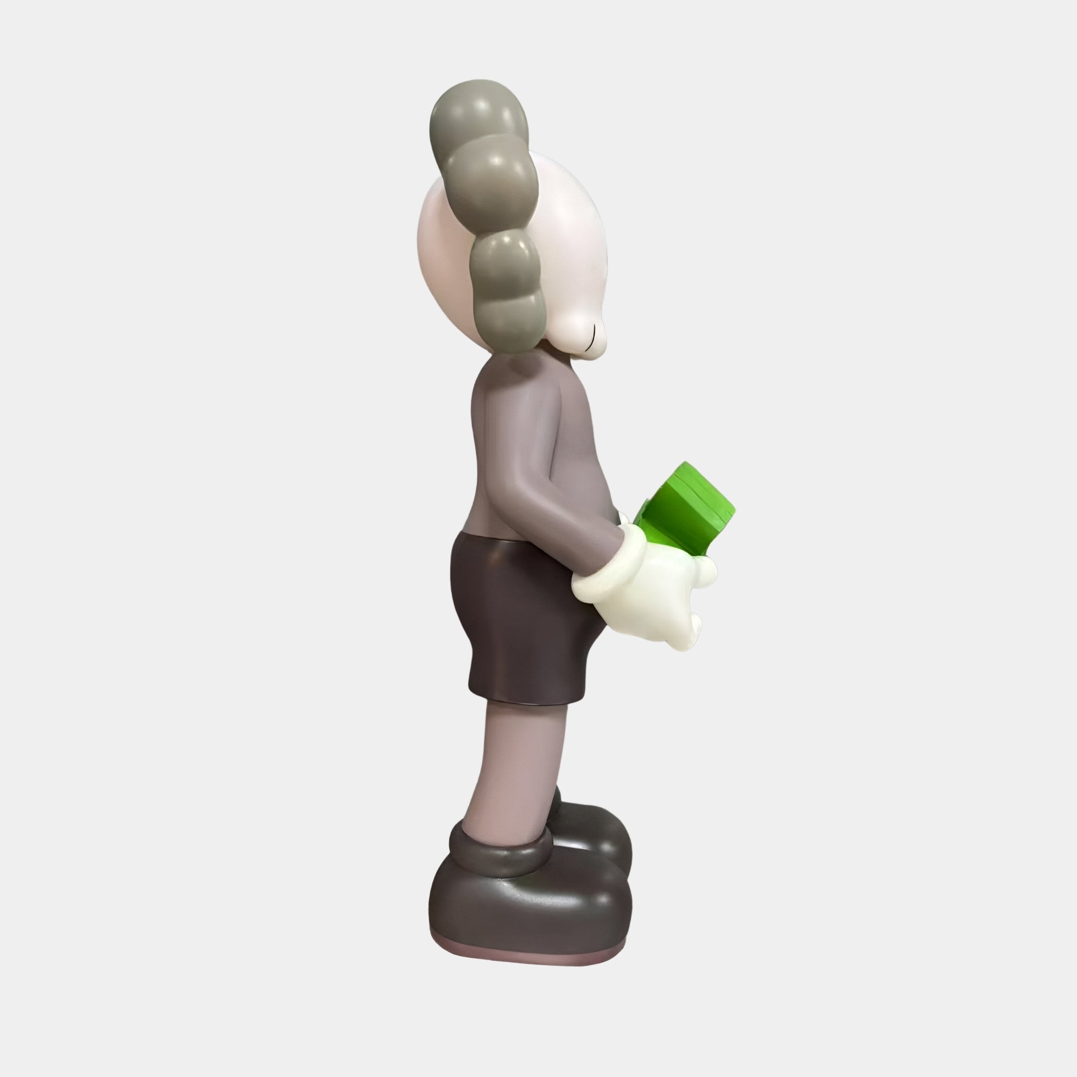 Side view of the Giant Sculptures Driftwood Grey Iconify Dollars Figure 30cm holding a green stack of cash behind its back, set against a plain light background.