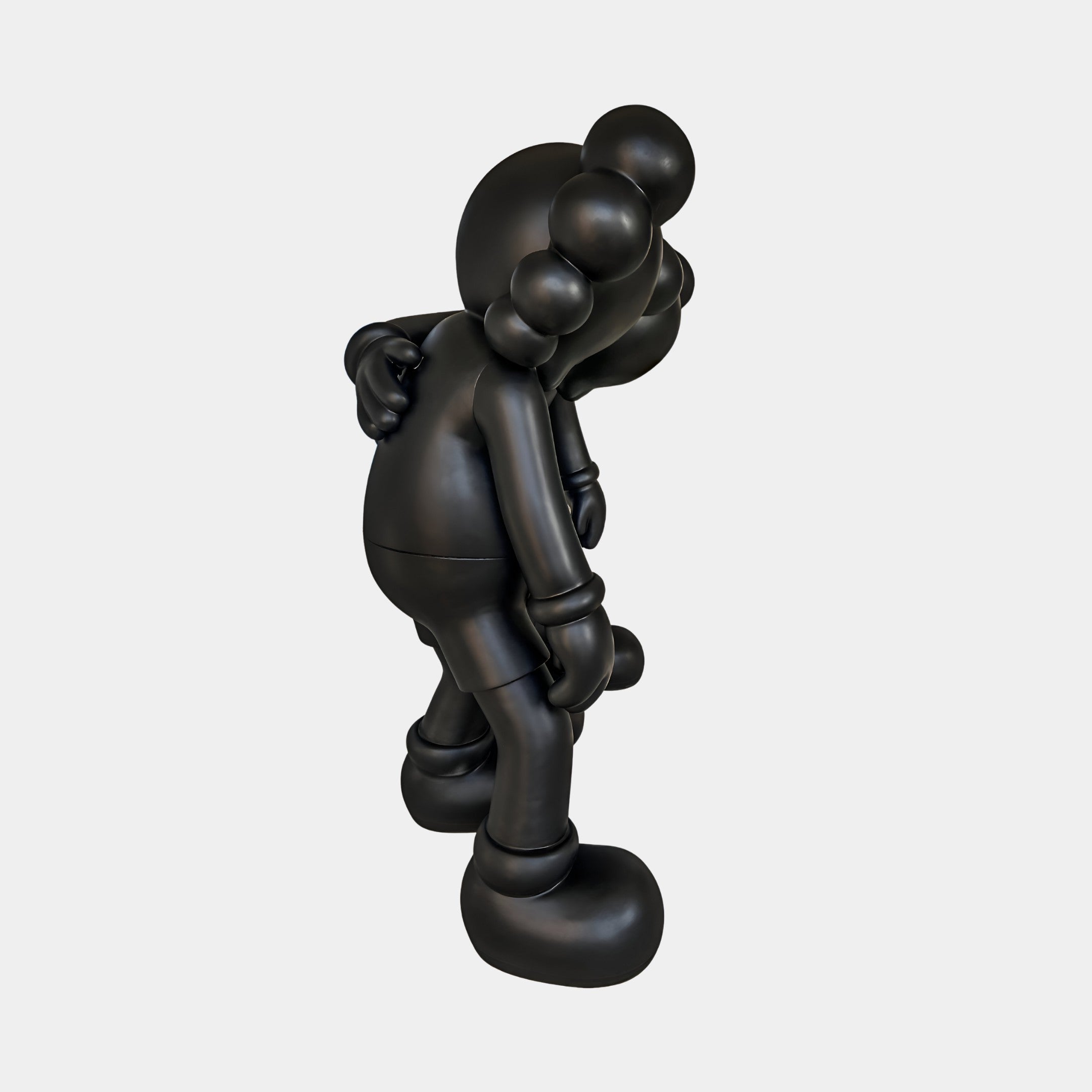 The Midnight Black Iconify Friendship Sculpture by Giant Sculptures (150cm) features a matte black, cartoonish figure with gloved hands and oversized shoes, bending forward—ideal as a modern resin art piece against a plain white backdrop.