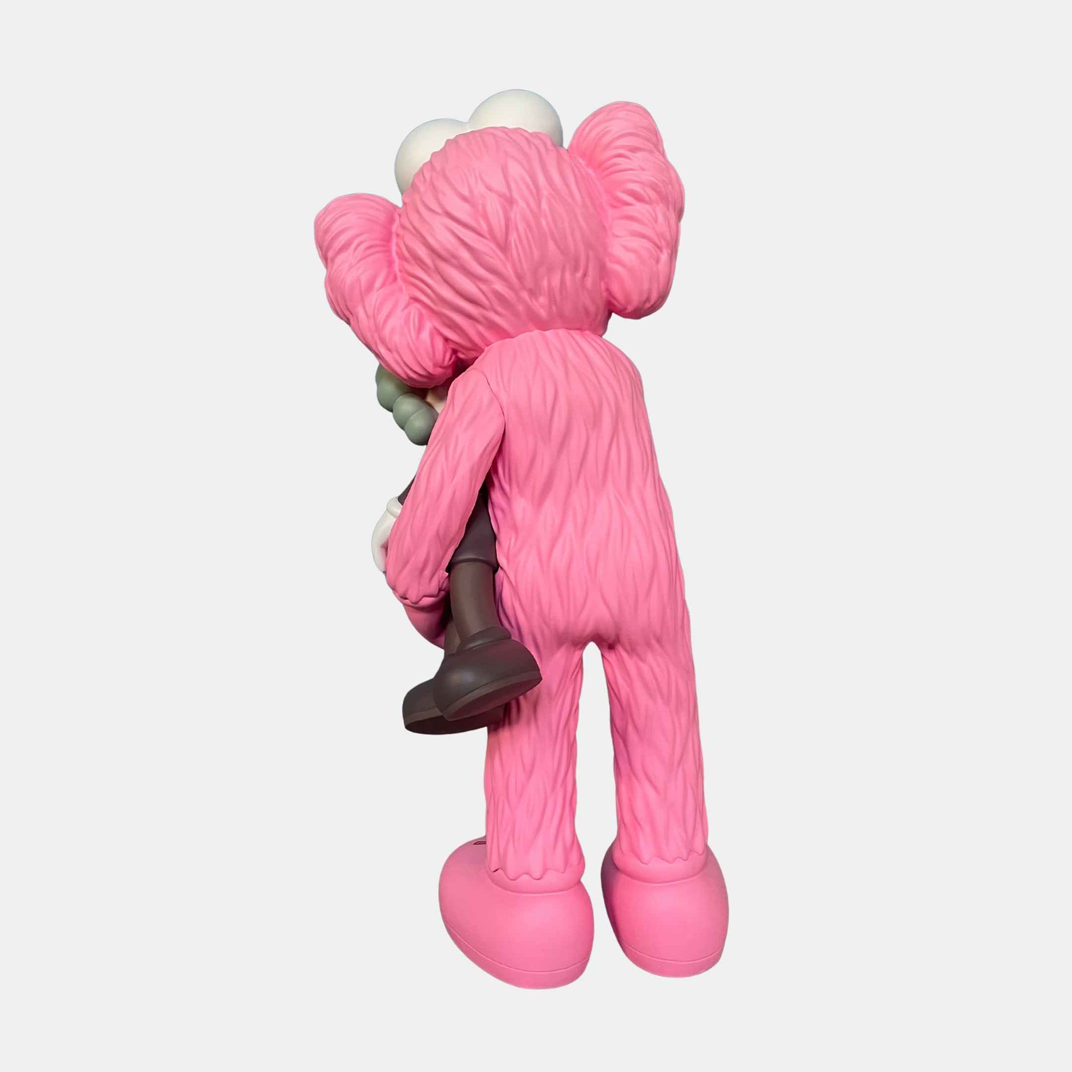 The Giant Sculptures Petal Pink Iconify Loving Furry Sculpture - 135cm features a whimsical pink figure holding a smaller gray and white companion, both with oversized hands and feet, making unique artistic home decor against a white background.