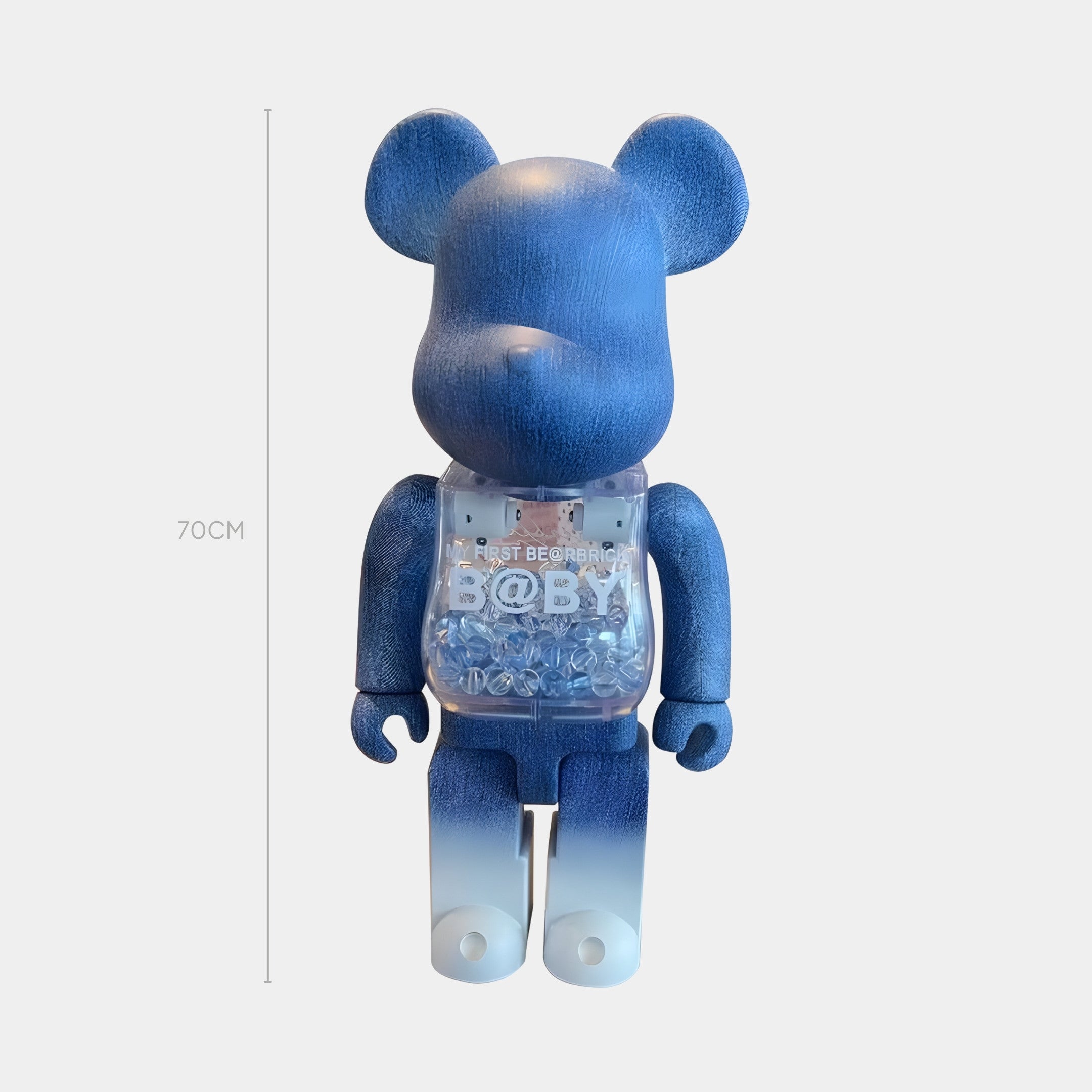 The Indigo Fade Bear Sculpture - 70cm by Giant Sculptures features a blue gradient, denim-print finish, a clear chest with BABY and beads inside, and stands upright next to a line marking its 70 cm height.